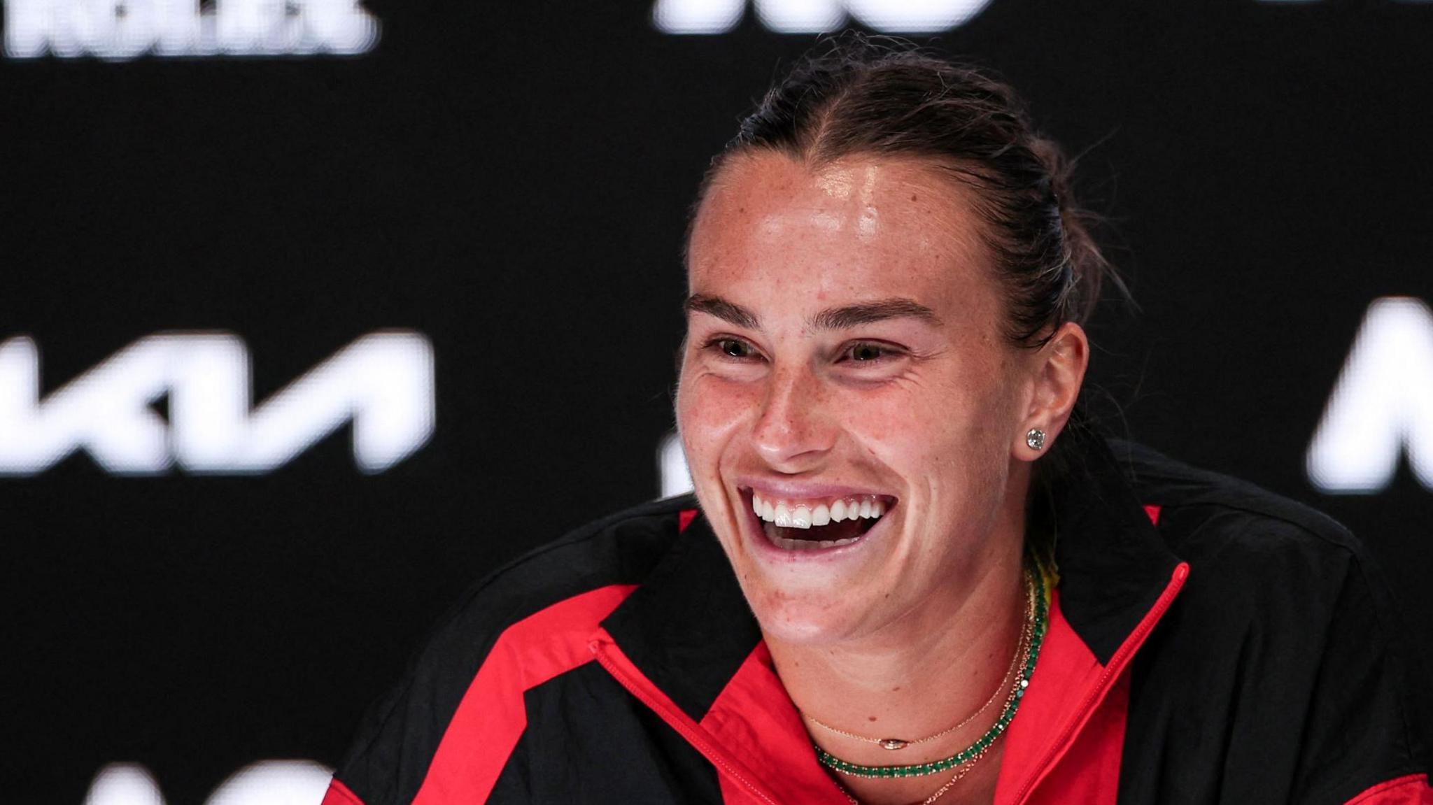 Aryna Sabalenka laughs during her post-match news conference