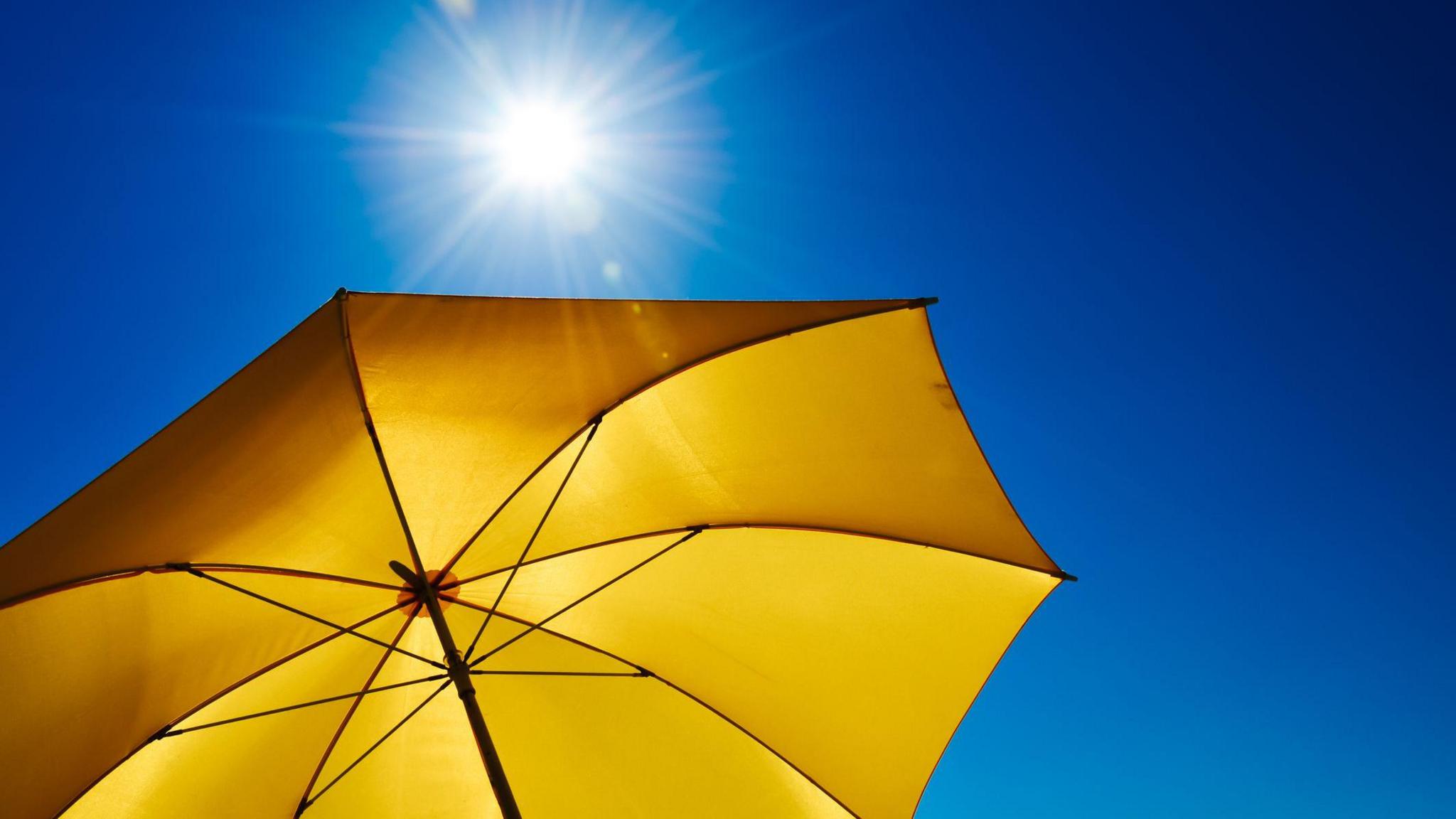 blue skies and strong sunshine with a bright yellow umbrella.