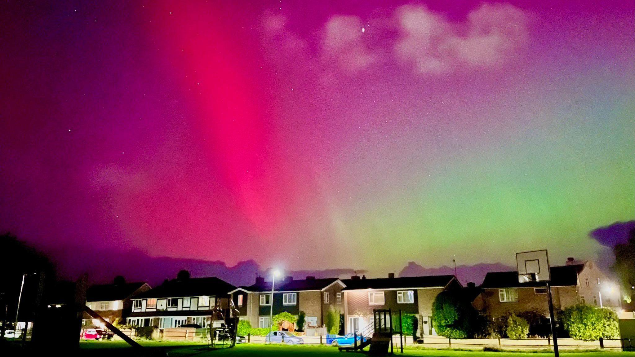 Northern Lights on display in the skies over houses.