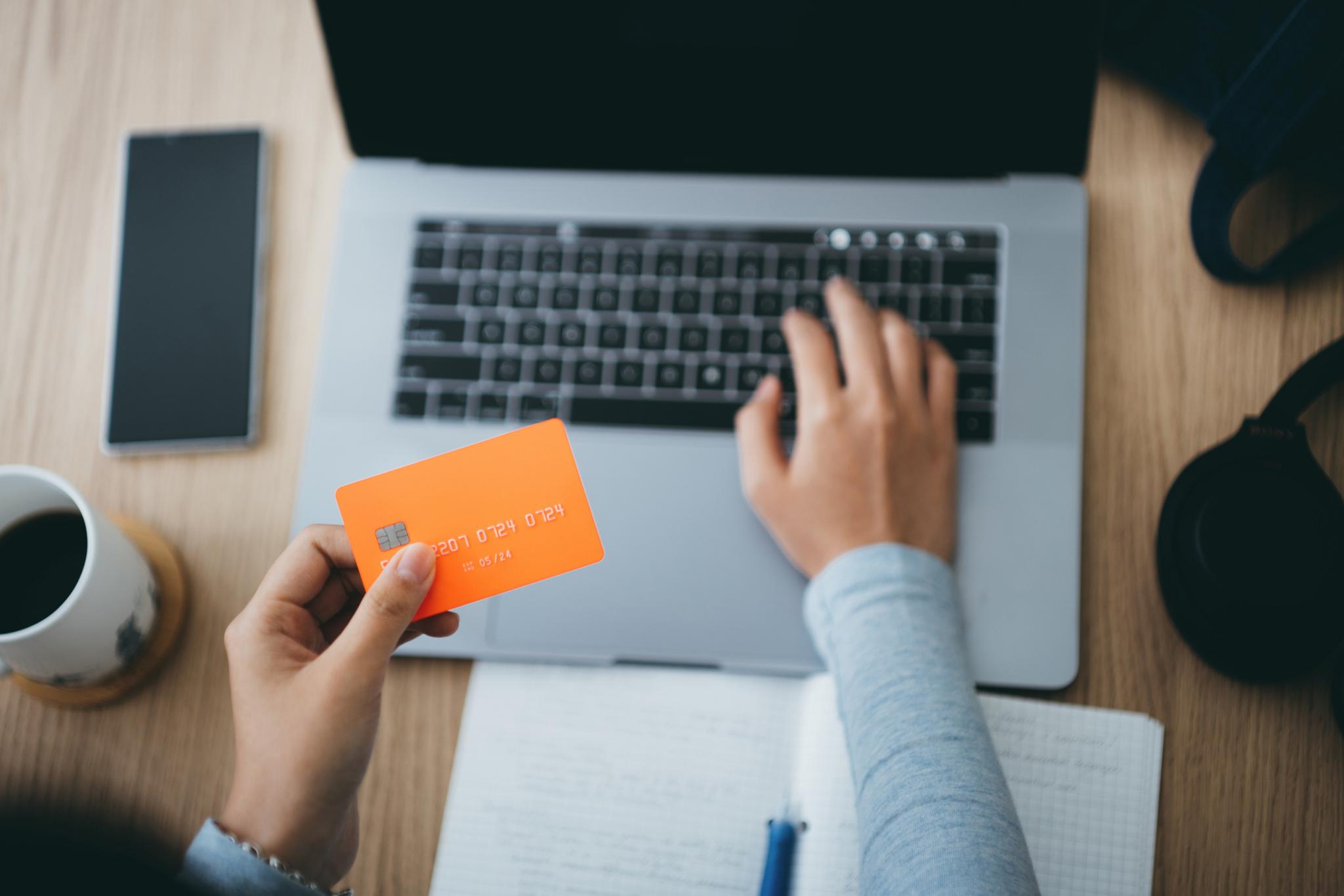 Woman using laptop with bank card in her hand