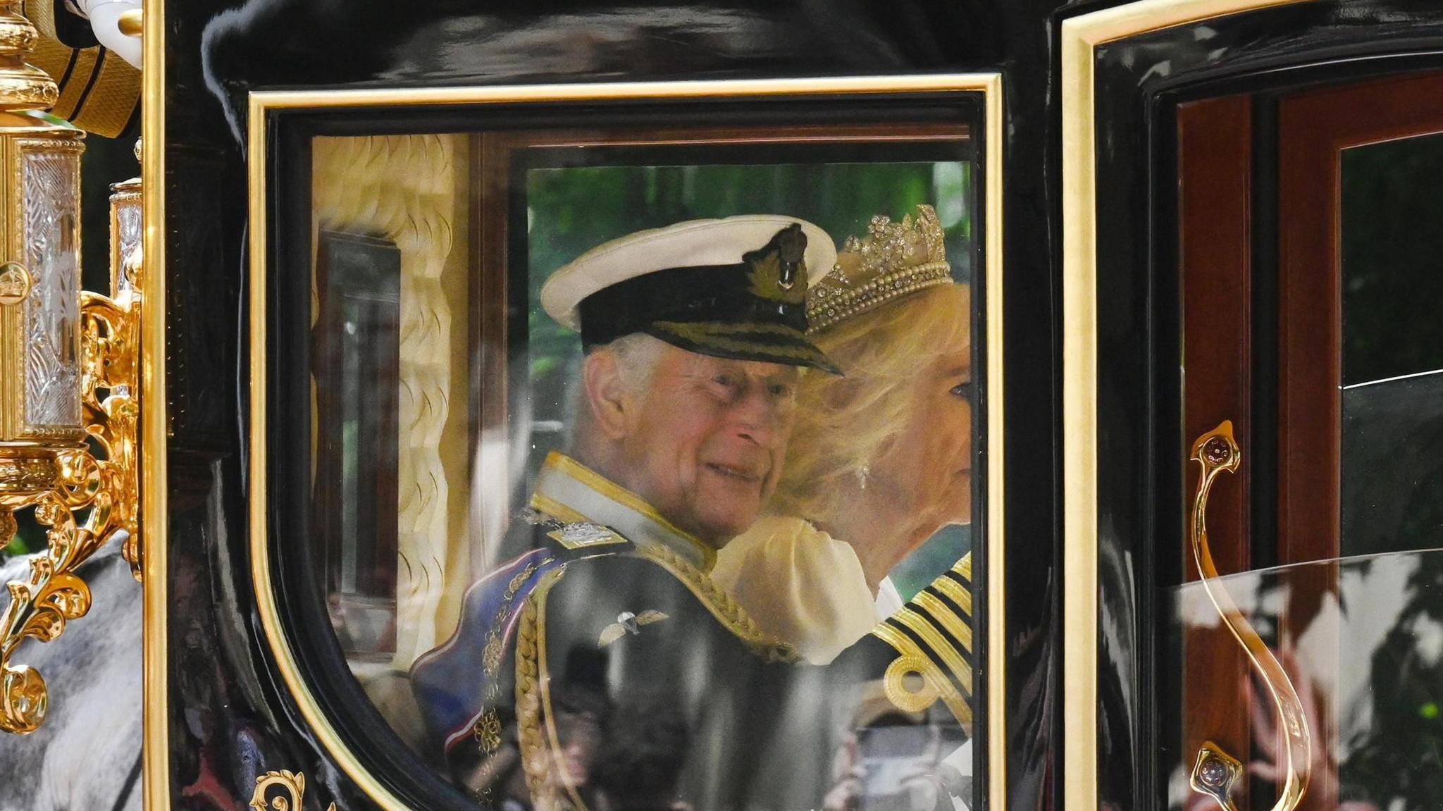 King Charles III and Queen Camilla wave from the Diamond Jubilee State Coach as they head along The Mall for the King's Speech