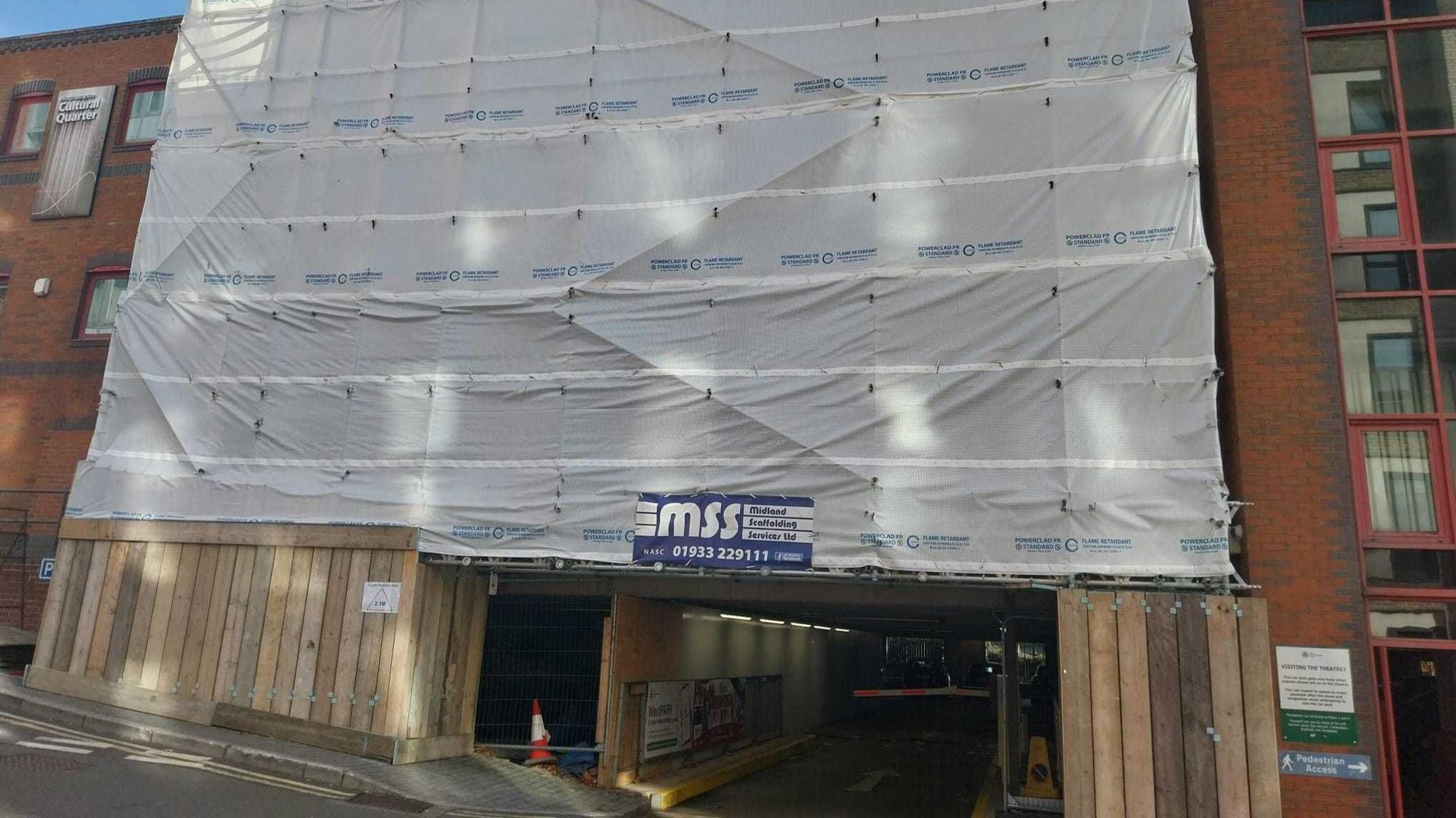 Outside view of a car park which has white sheeting covering part of the building