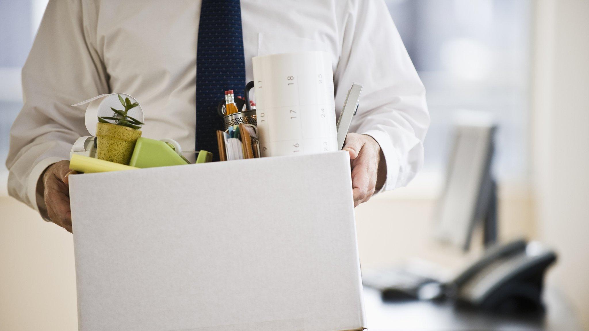 A man holds a box of work things