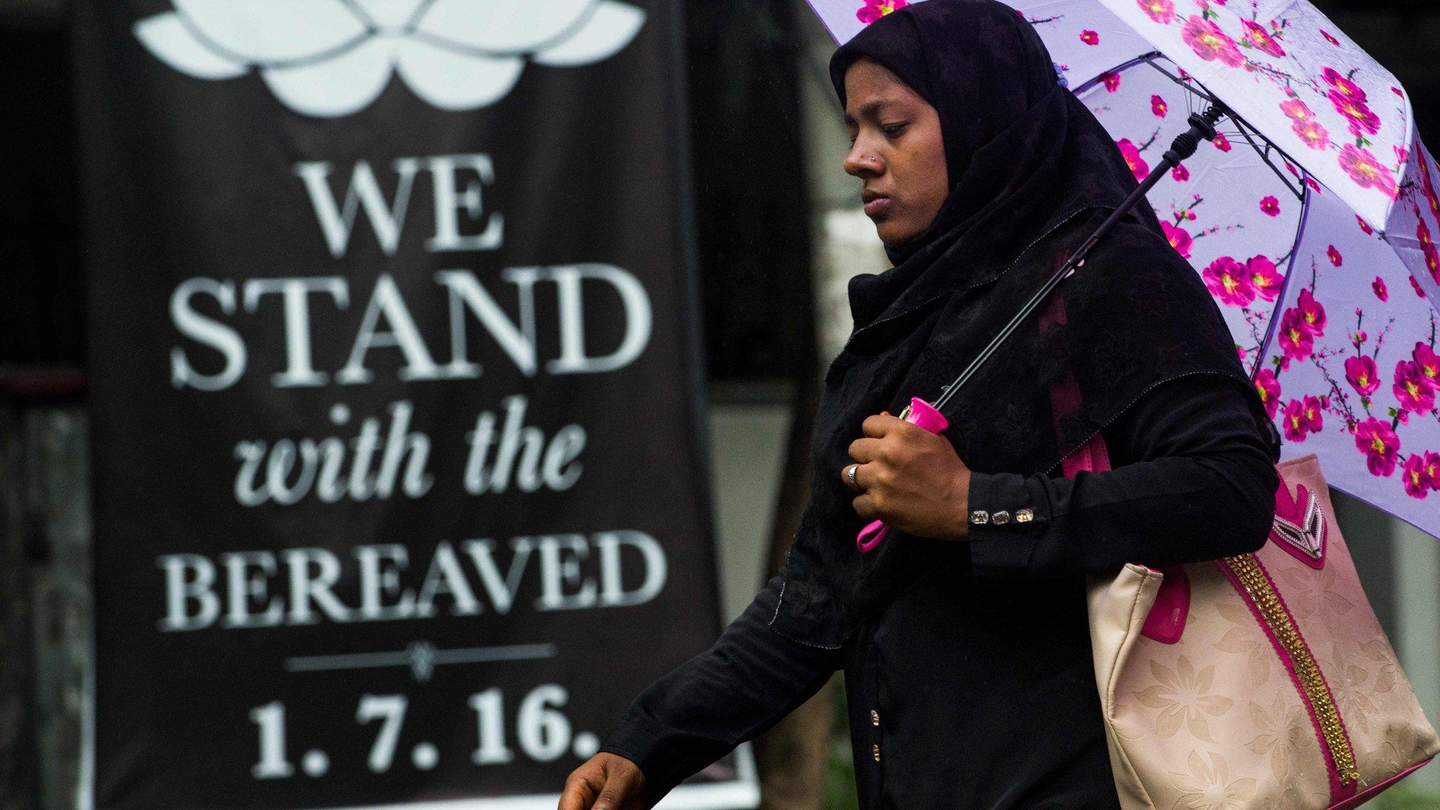 Bangladeshi woman walks past a banner