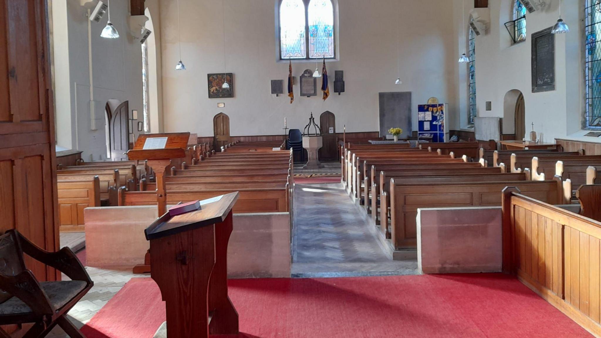 The inside of a church looking from the altar towards the wooden pews