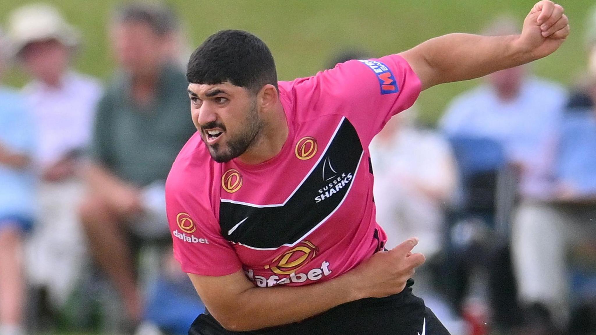 Dan Ibrahim bowls for Sussex in the One Day Cup, wearing a pink top and black trousers