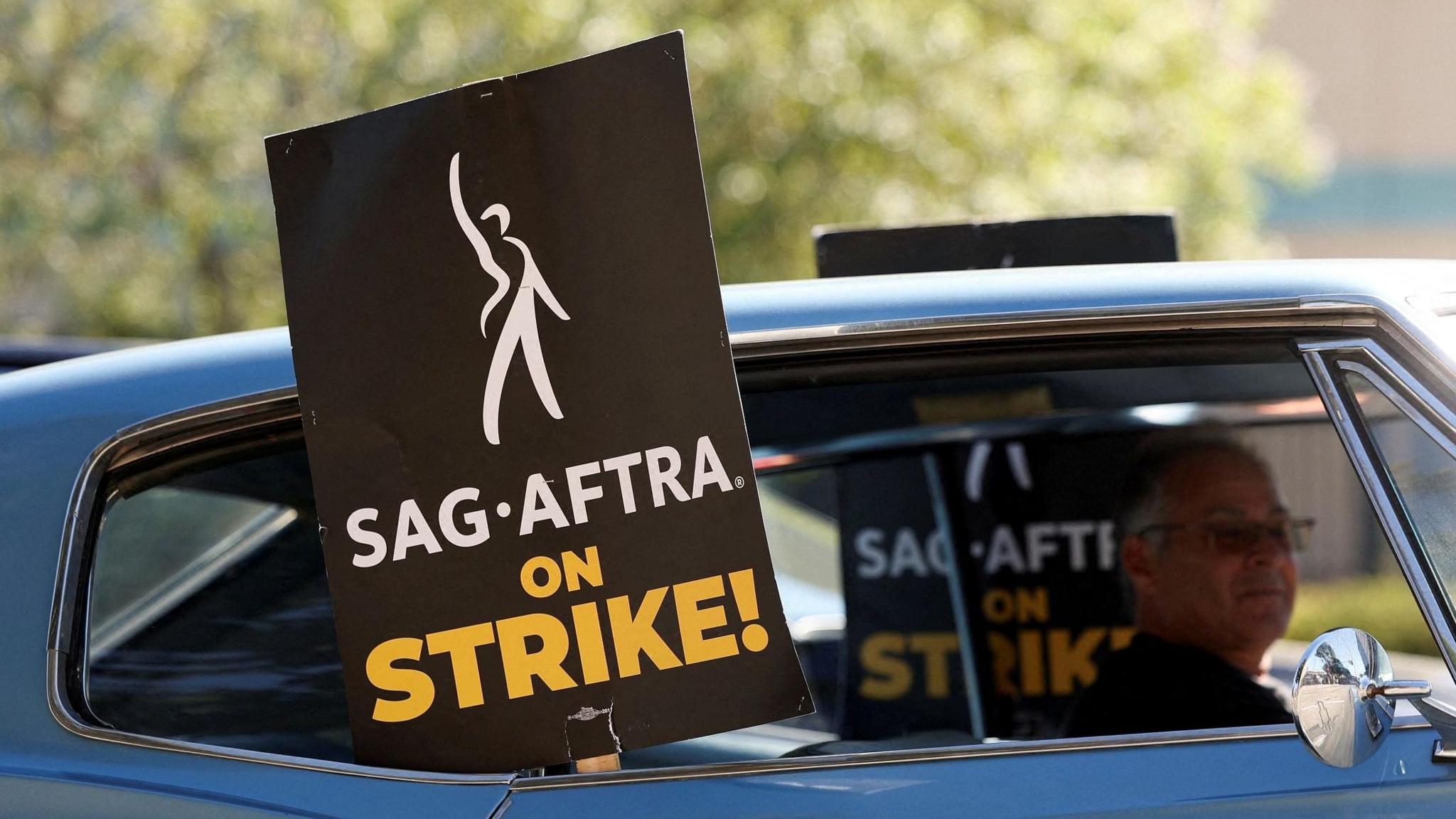 A mid shot of a sign saying "SAG AFTRA on STRIKE!"