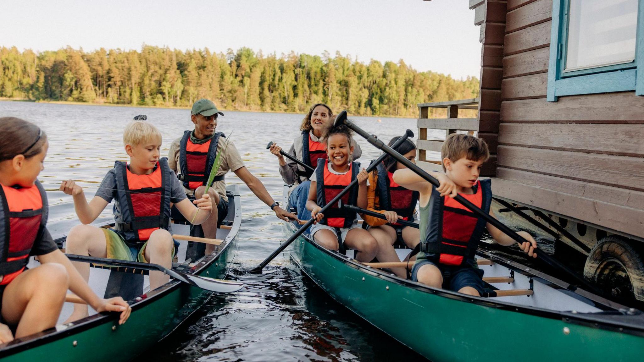 a group of children in two canoe boats with their teachers.
