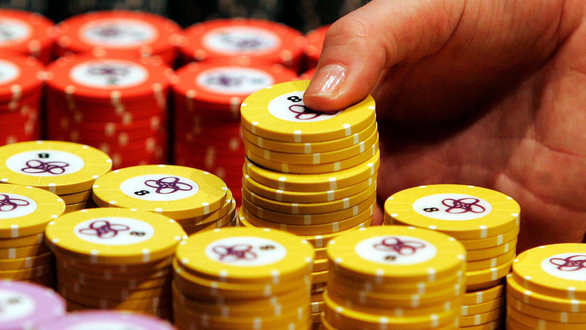 Several stacks of yellow and red gambling chips, with a close-up of a hand removing one stack.