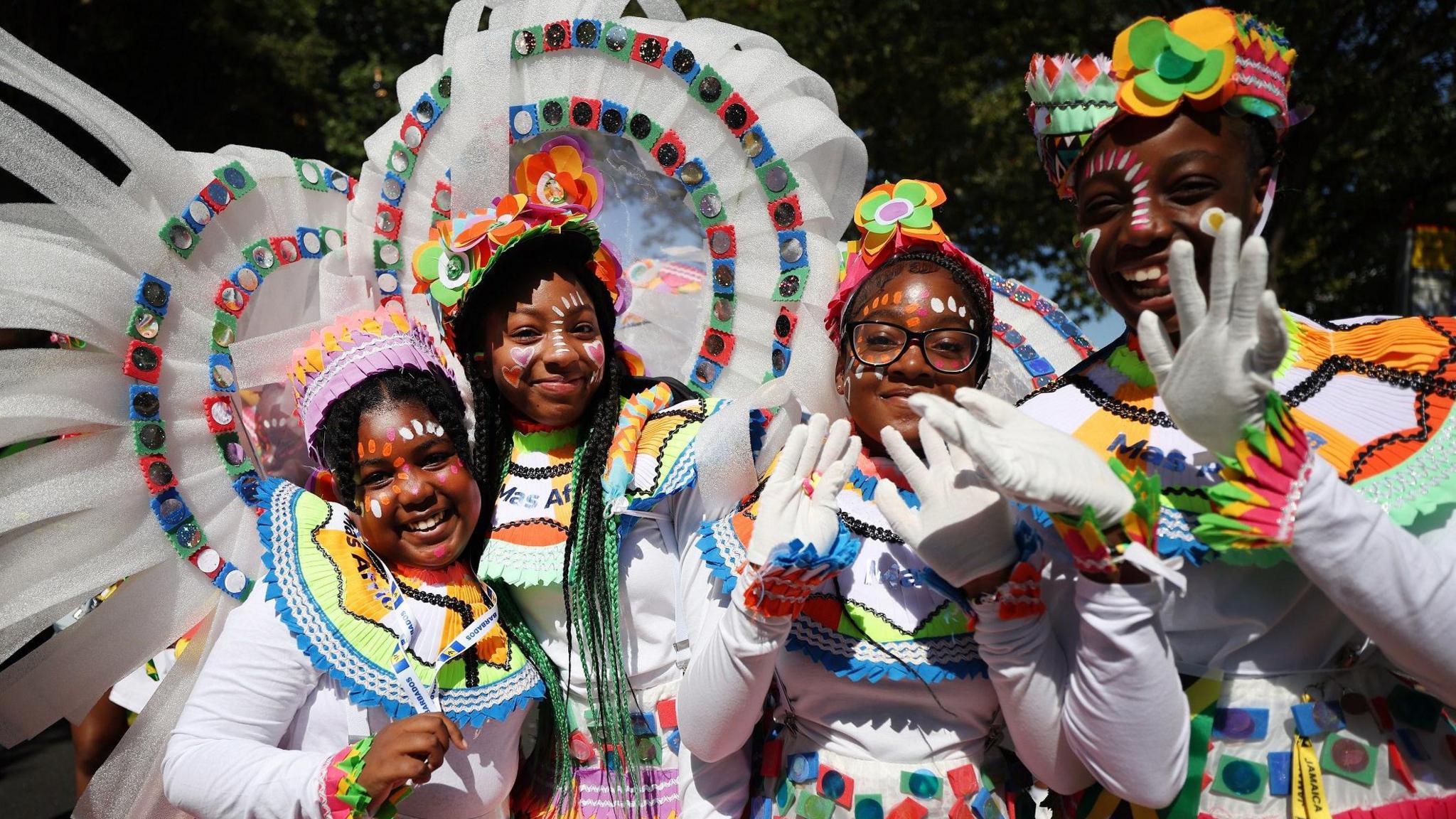 Four girls smiling and waving at the camera wearing colourful costumes.