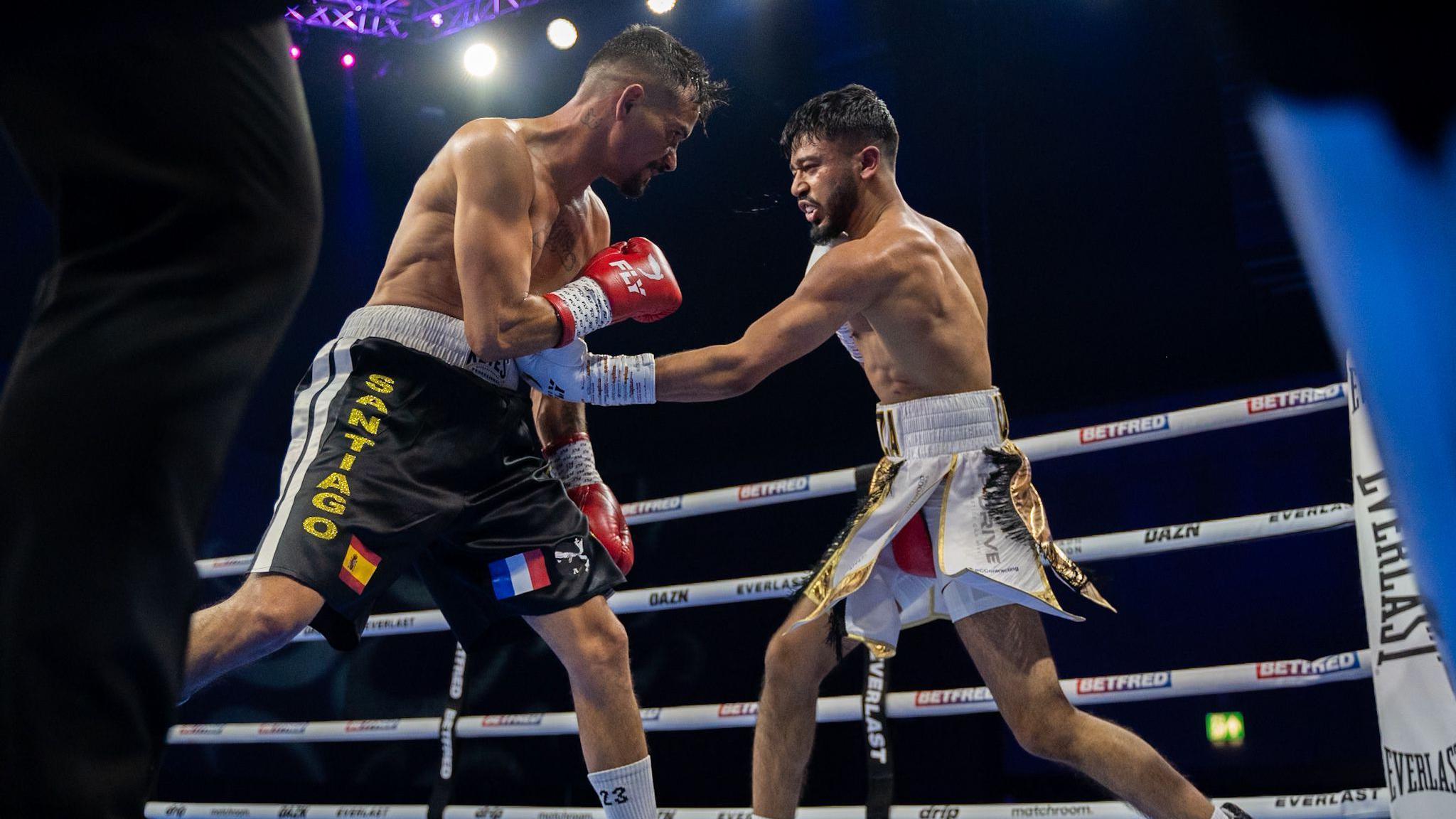 Hamza Uddin in a boxing ring with a component. Uddin is punching the opponent in the gut during a fight.