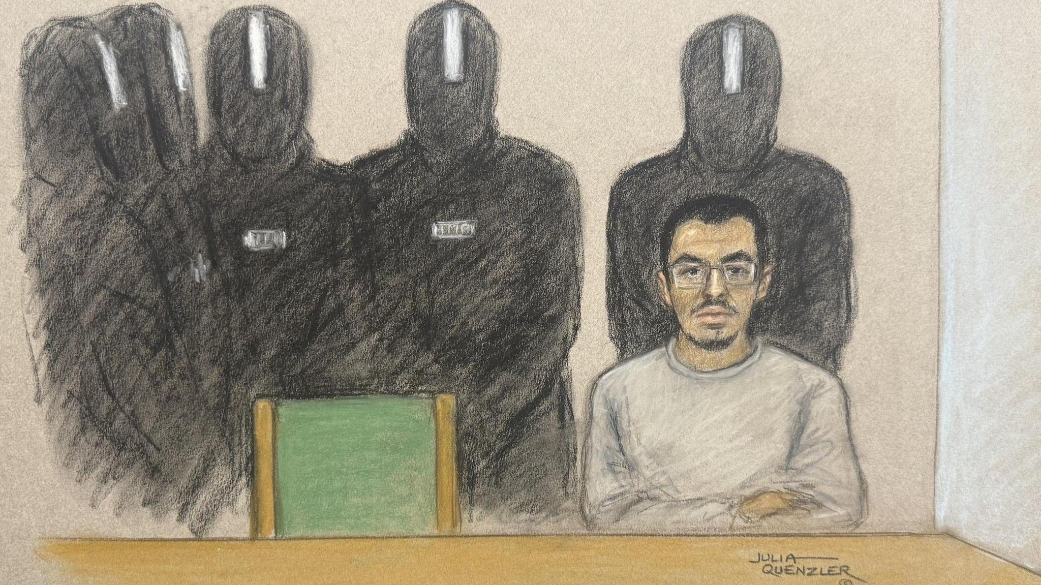 A coloured illustration of a young man sitting at a table with his arms folded and wearing a grey tracksuit. An empty green chair is next to him and five guards in masks and riot gear stand behind him. 