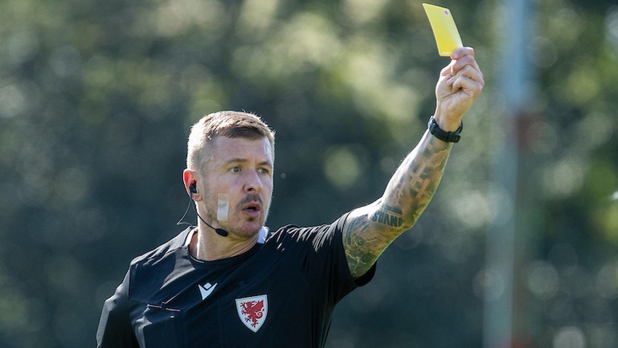 Referee Alex Livesey brandishes a yellow card at Mold Alexandra vs Holywell Town