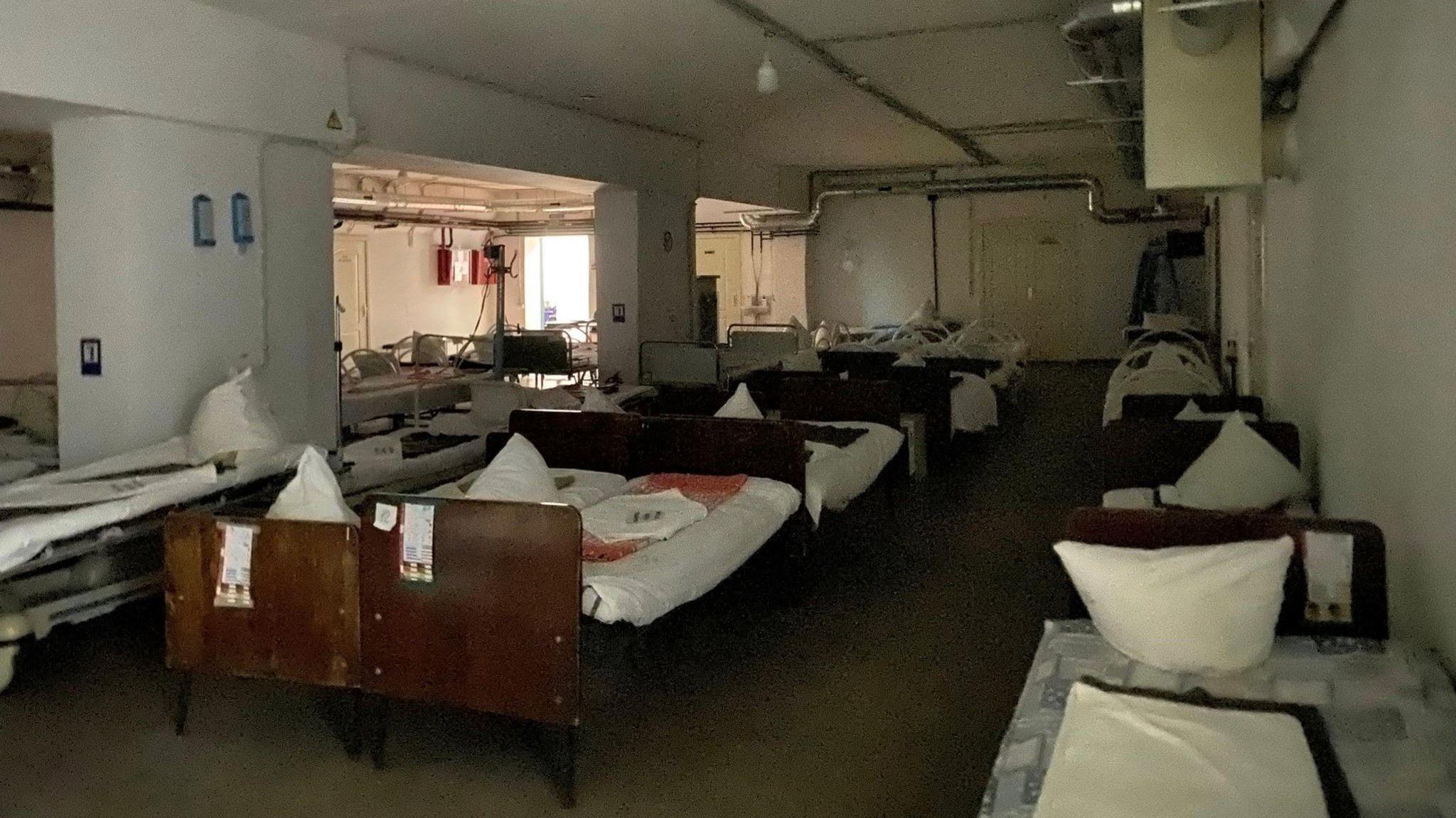 A view of the inside of an air raid shelter in Kyiv, with lots of set up beds in rows next to each other.