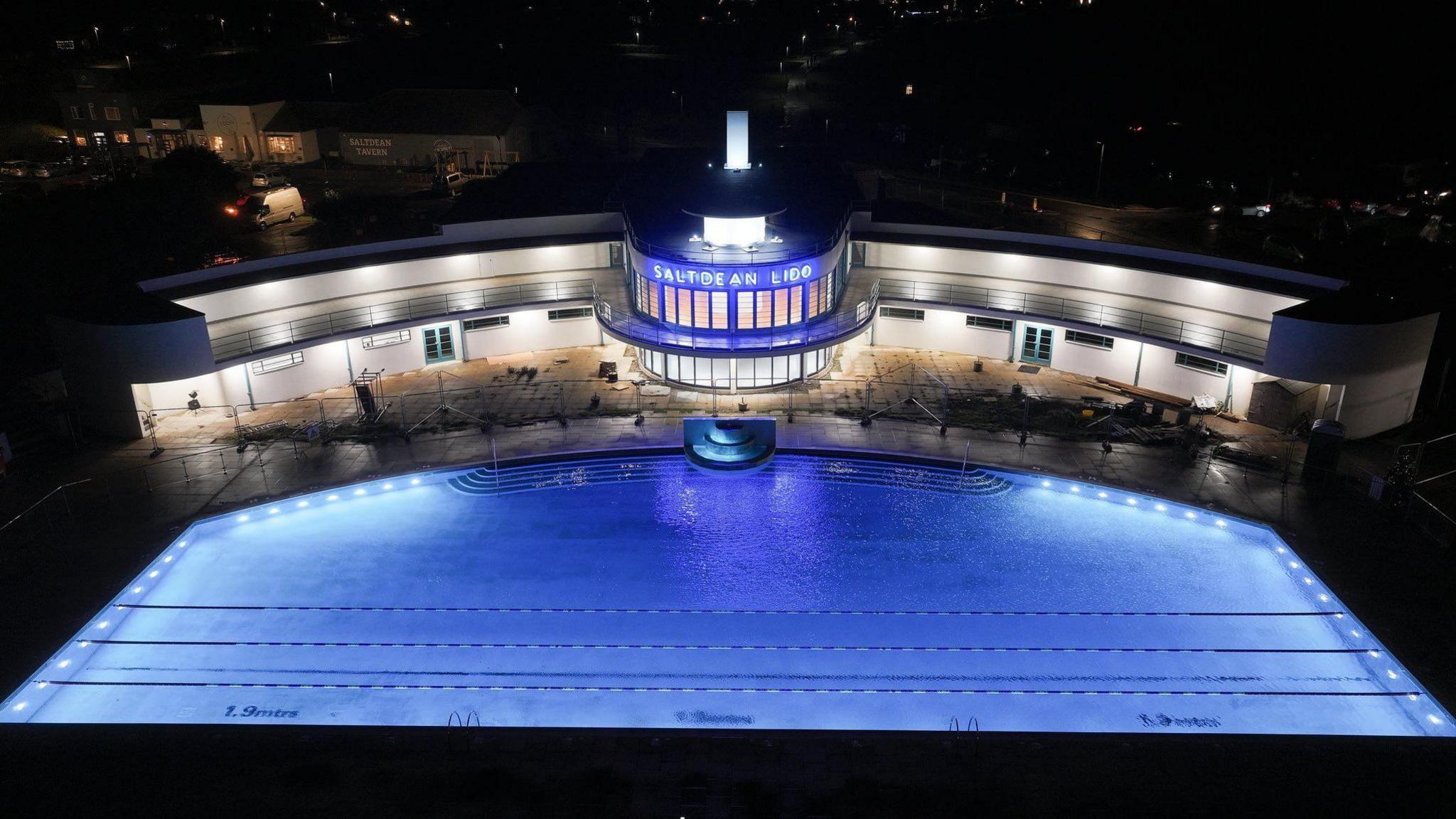 Blue neon sign which reads Saltdean Lido overlooking the pool at Saltdean Lido