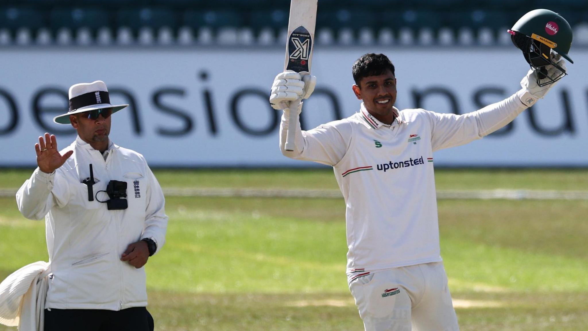 Rishi Patel raises his bat and helmet after completing a century against Kent