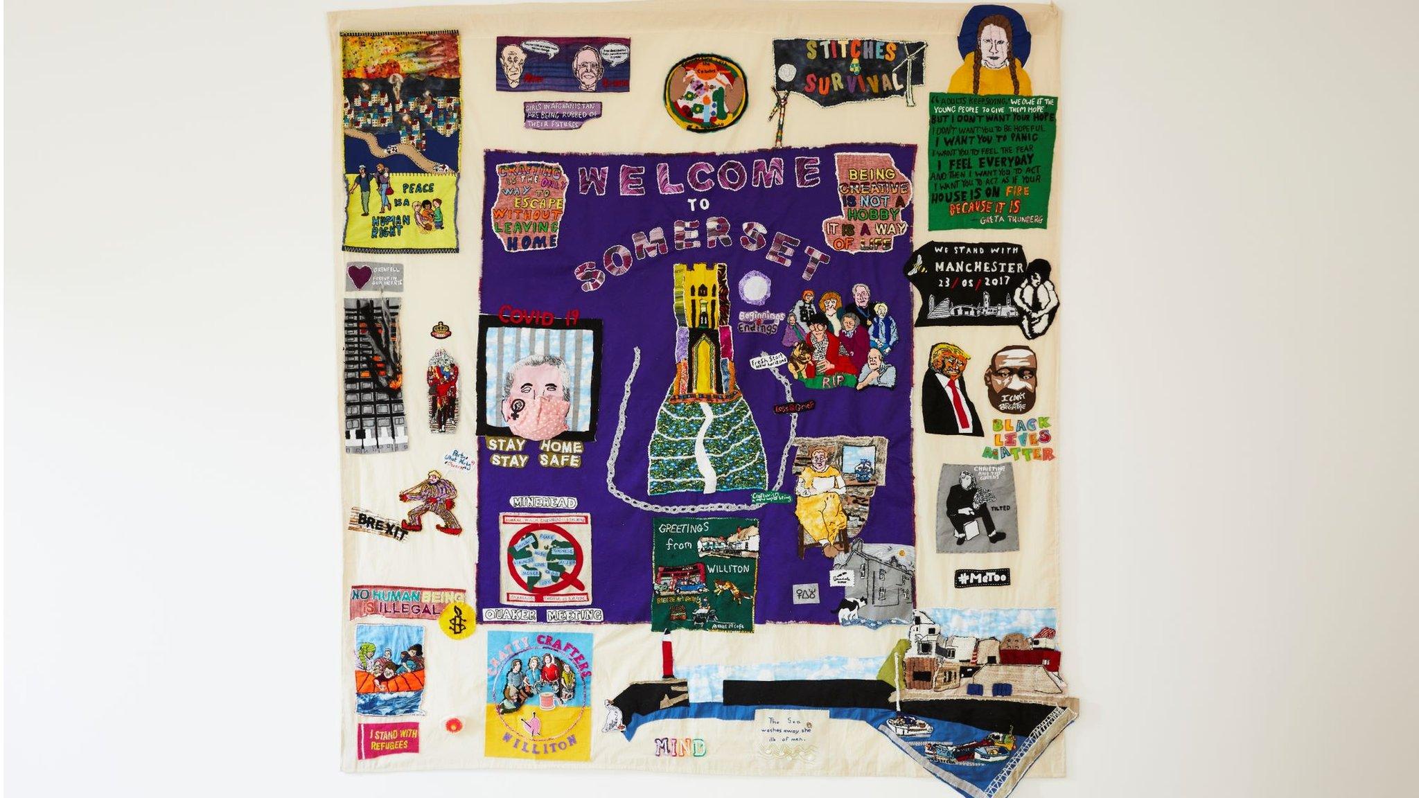 A colourful tapestry hanging on a white wall with a purple centre saying Welcome to Somerset and imagery from the 2000s including Donald Trump and the words Black Lives Matter