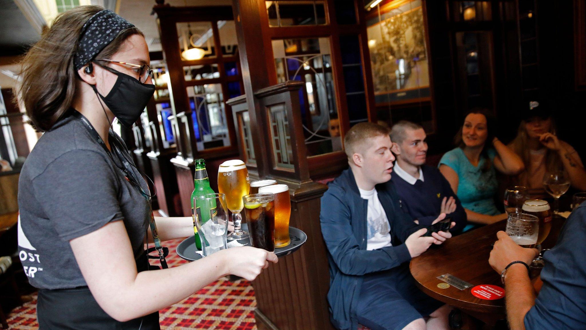 A bar worker serves customers at the Goldengrove pub in Stratford, east London