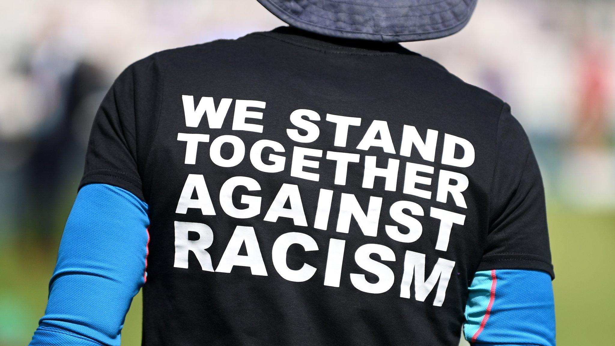 An England cricketer wears a black t-shirt with the message "We stand together against racism" on the back before a Test match