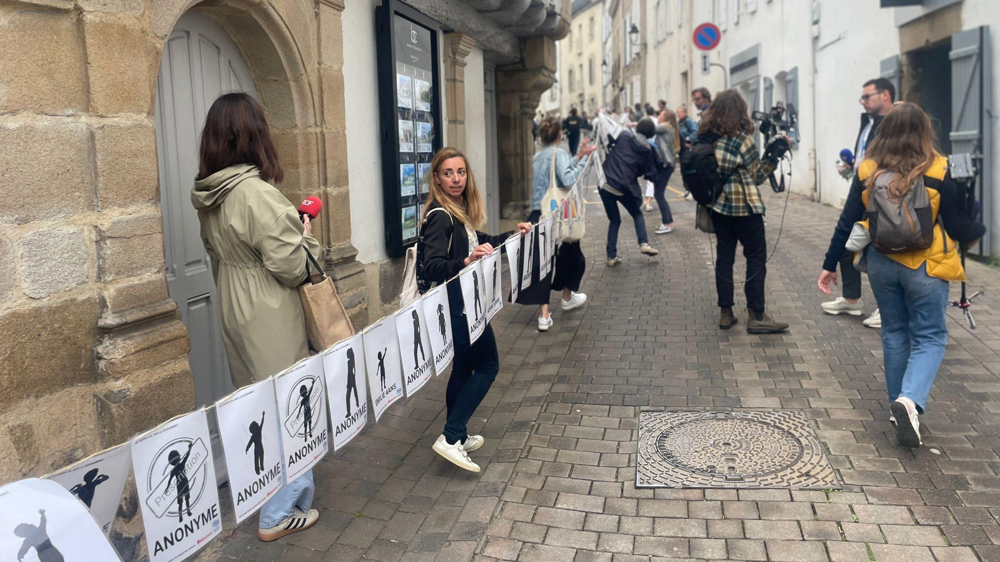 A long banner representing the many victims of Le Scouarnec being unfurled in the streets of Vannes