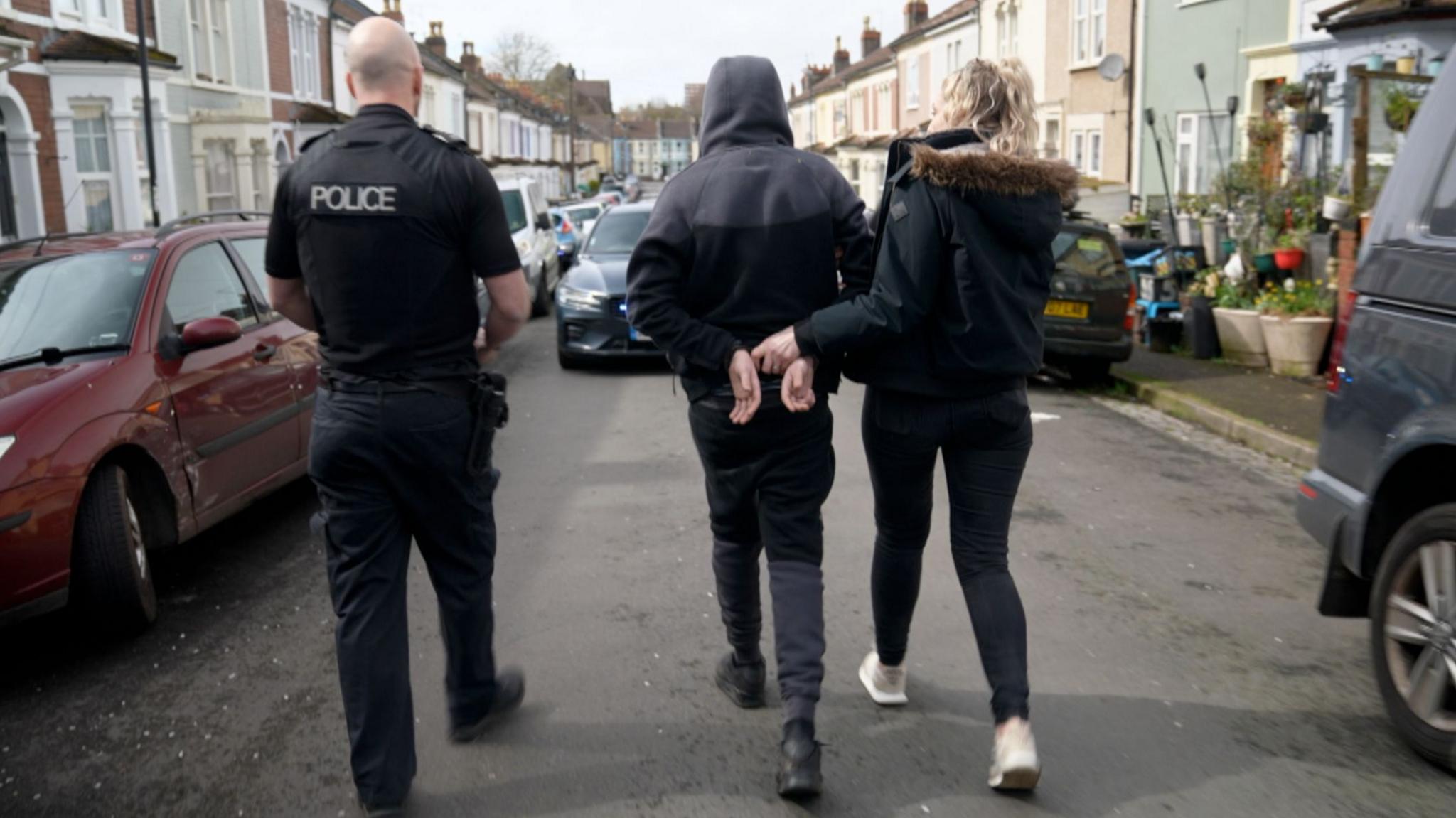 Police escort one of the teenagers from the car away from the scene