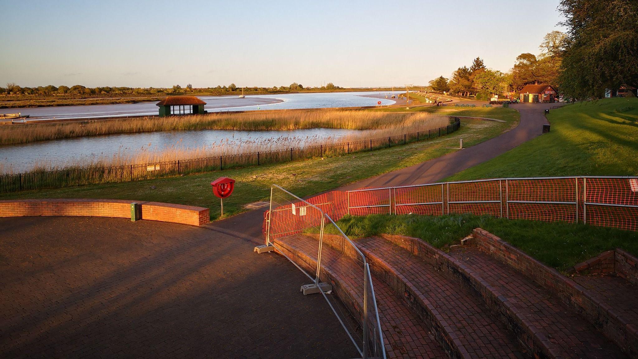 A close up of one side of the amphitheatre under the light of a sunset, bodies of water far off in the background