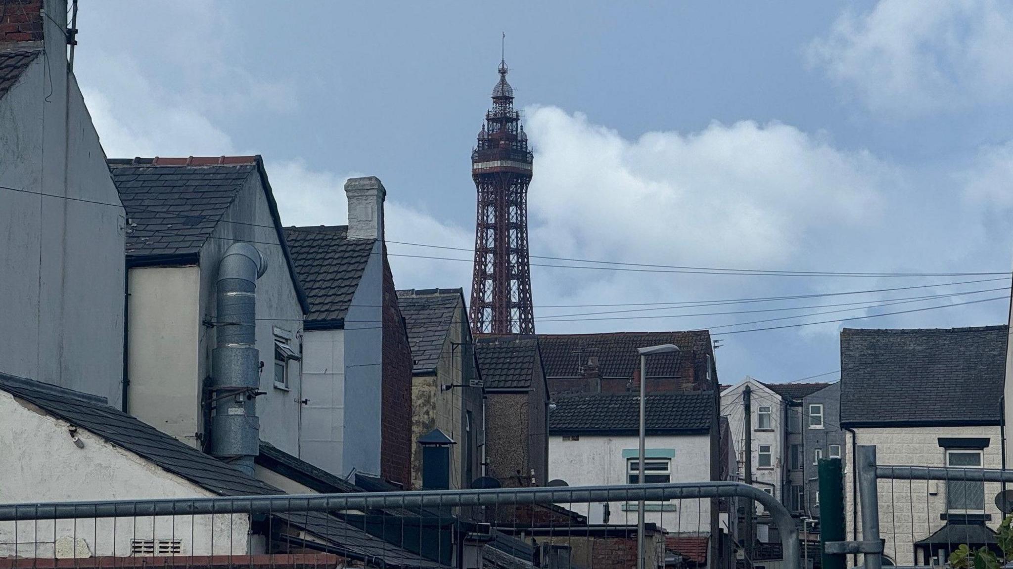 The Blackpool tower against a backdrop of blue sky, with residential buildings in the foreground