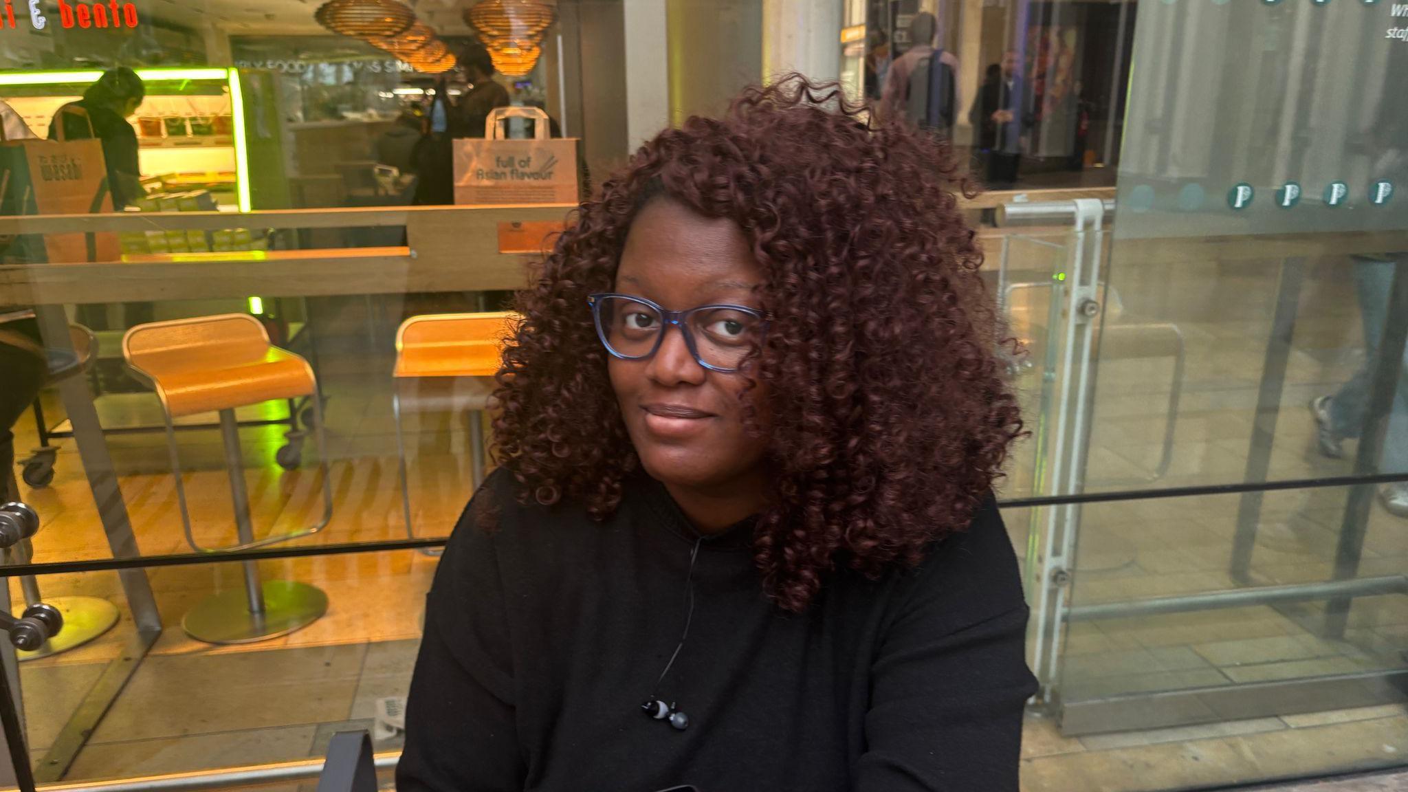 Mariama Bundu sat in front of a takeaway restaurant in Paddington
