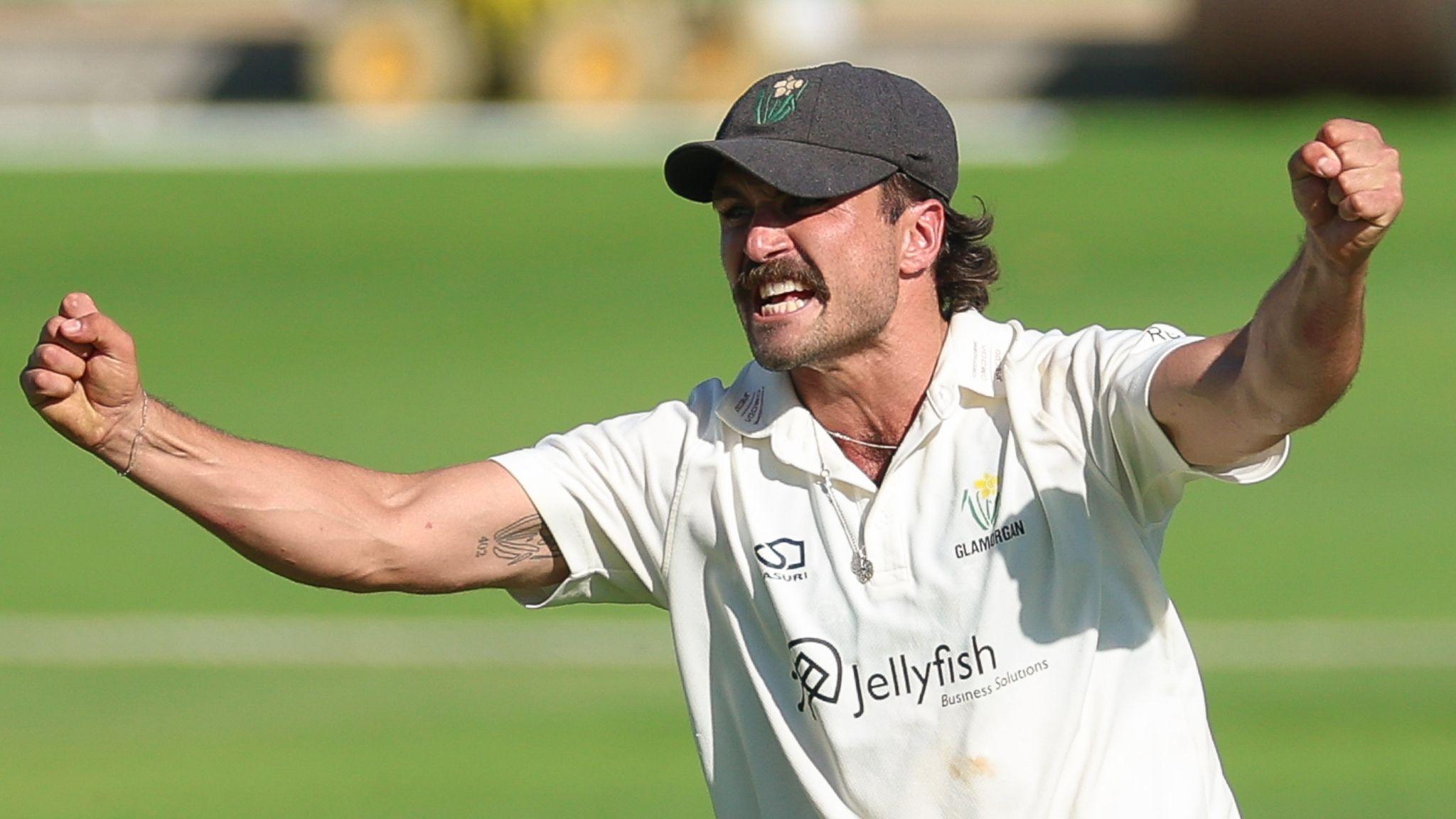 Kiran Carlson wearing a cap with clenched fists and and arms out wide in celebration
