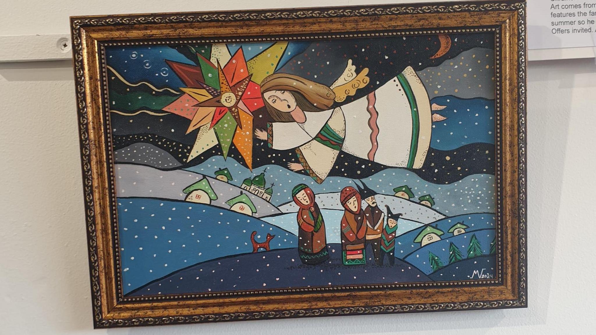 A painting with a brown frame. In the painting there is an angel flying over homes and three men. There is a dog in the painting and a star.