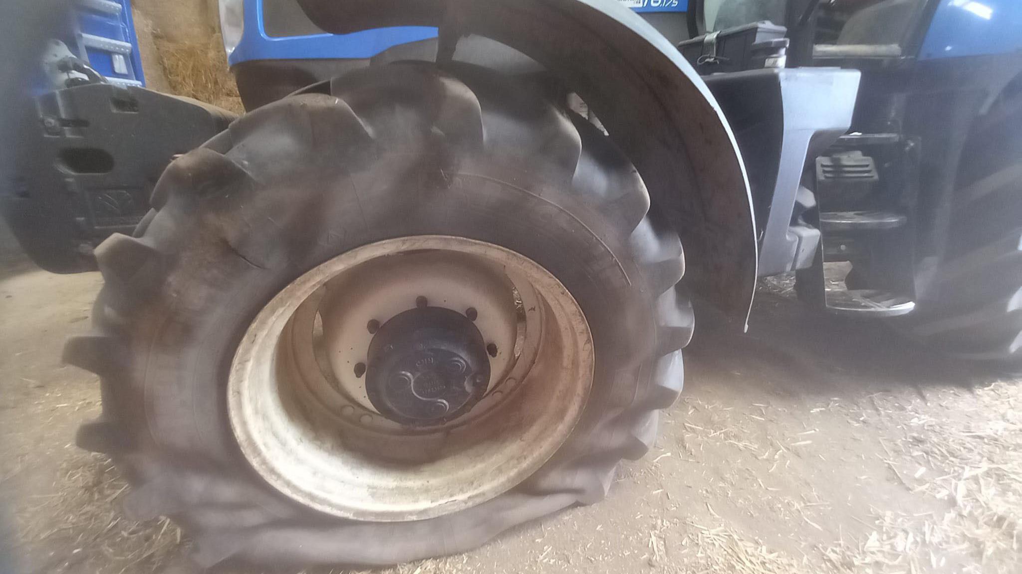 A blue tractor with a large deflated tyre.