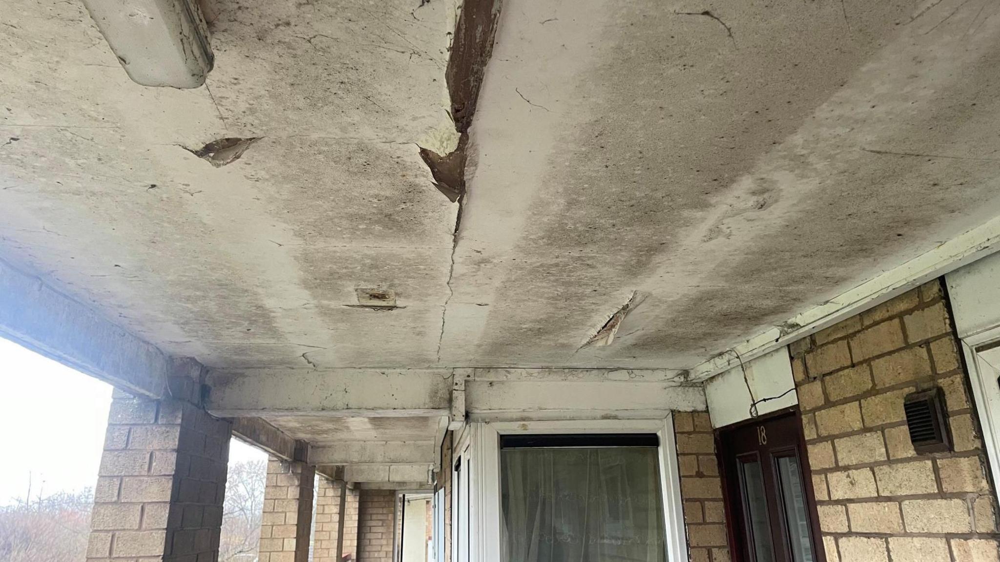 The ceiling of a communal corridor in a block of flats covered in moulf