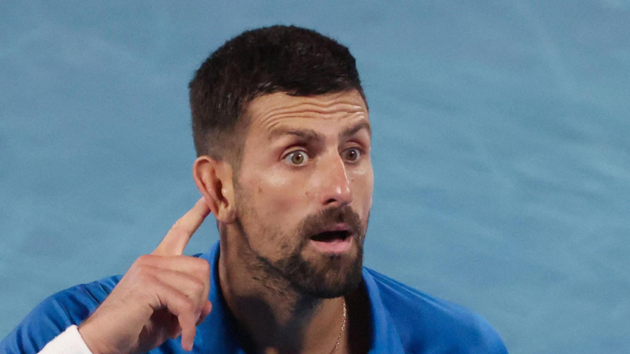 Novak Djokovic cups his ear to the Melbourne crowd