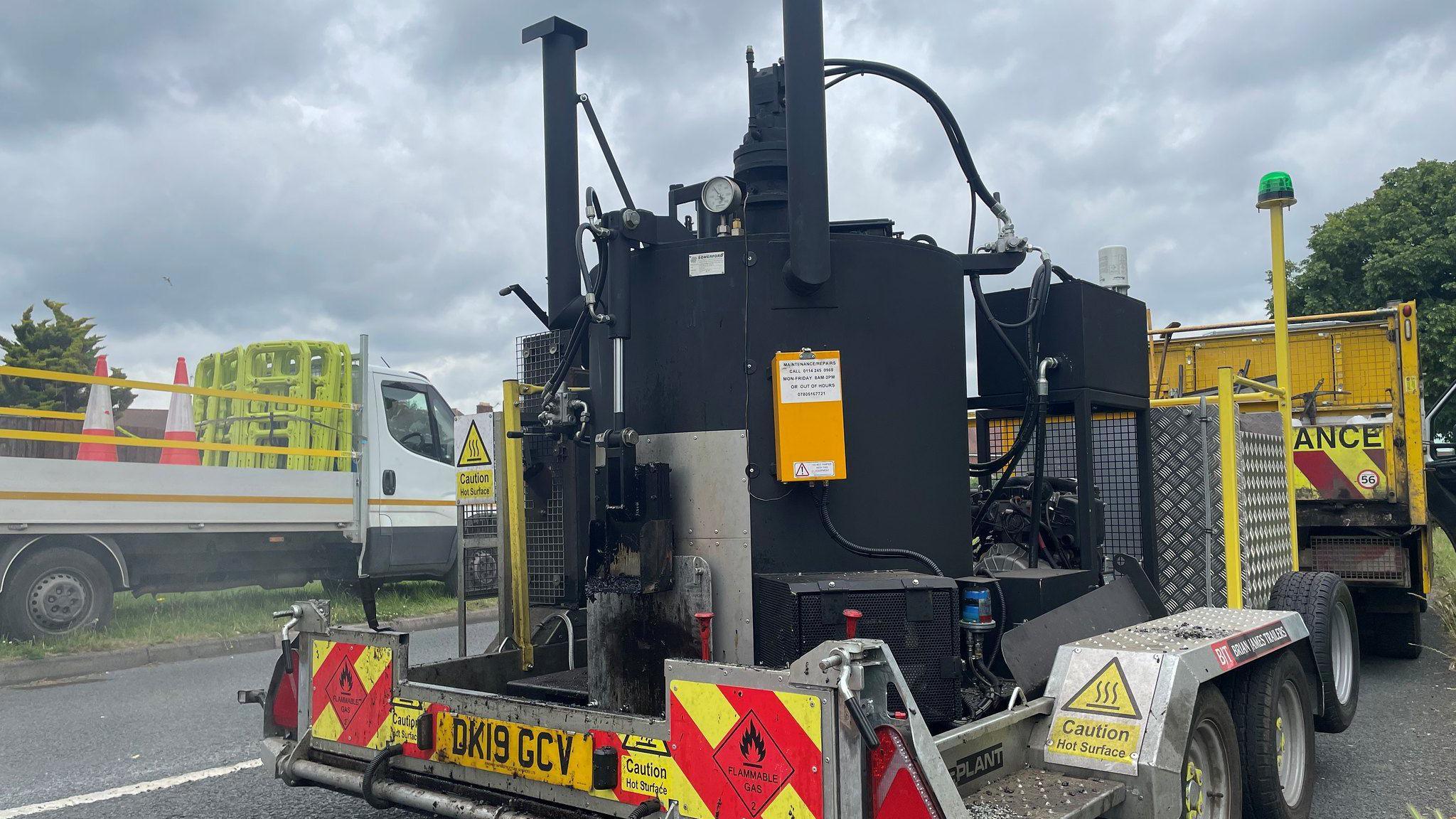 Black trailer mounted machine that fills potholes