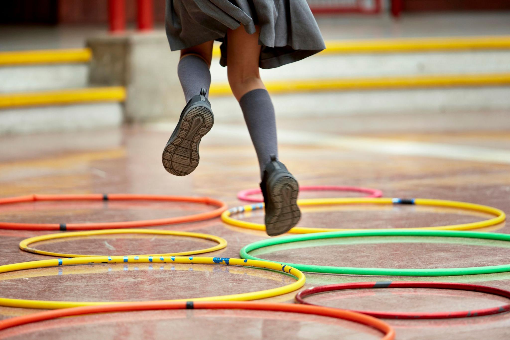 Child jumping through hoops wearing school socks and shoes