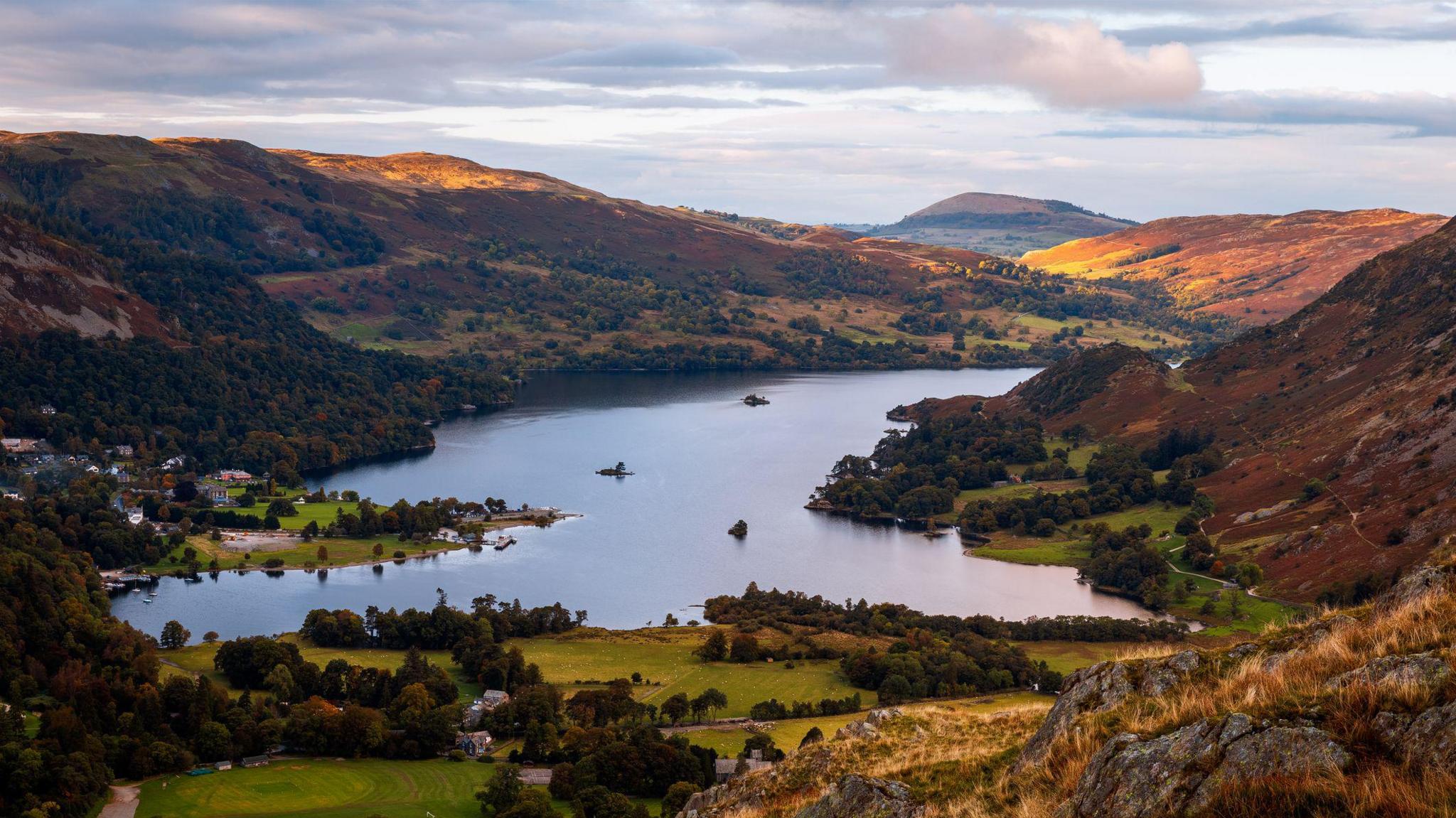 Aerial view of Ullswater and the surrounding fells. A number of houses and other properties are dotted around the water's edge.