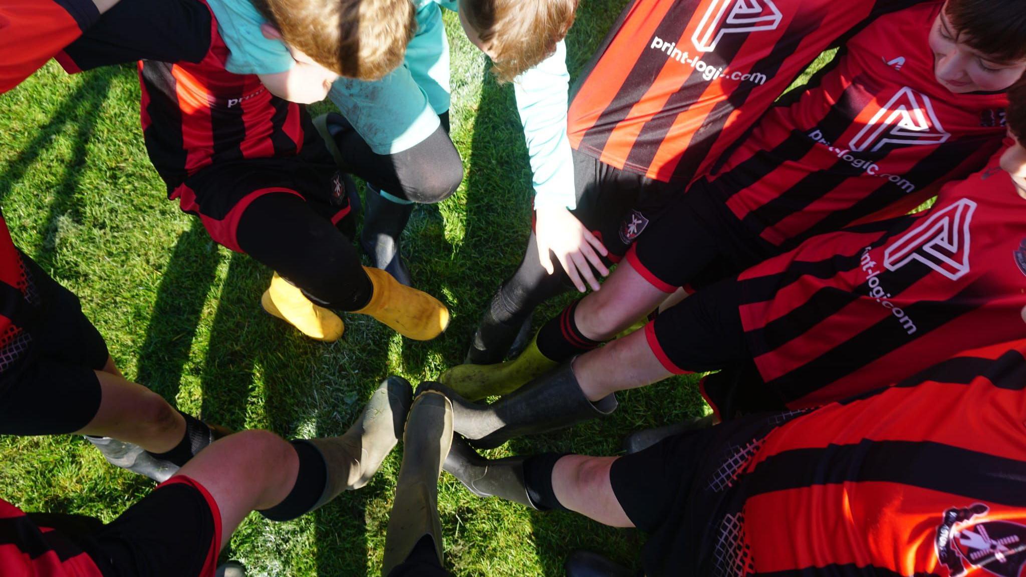 The team putting their feet in the middle with their wellies on