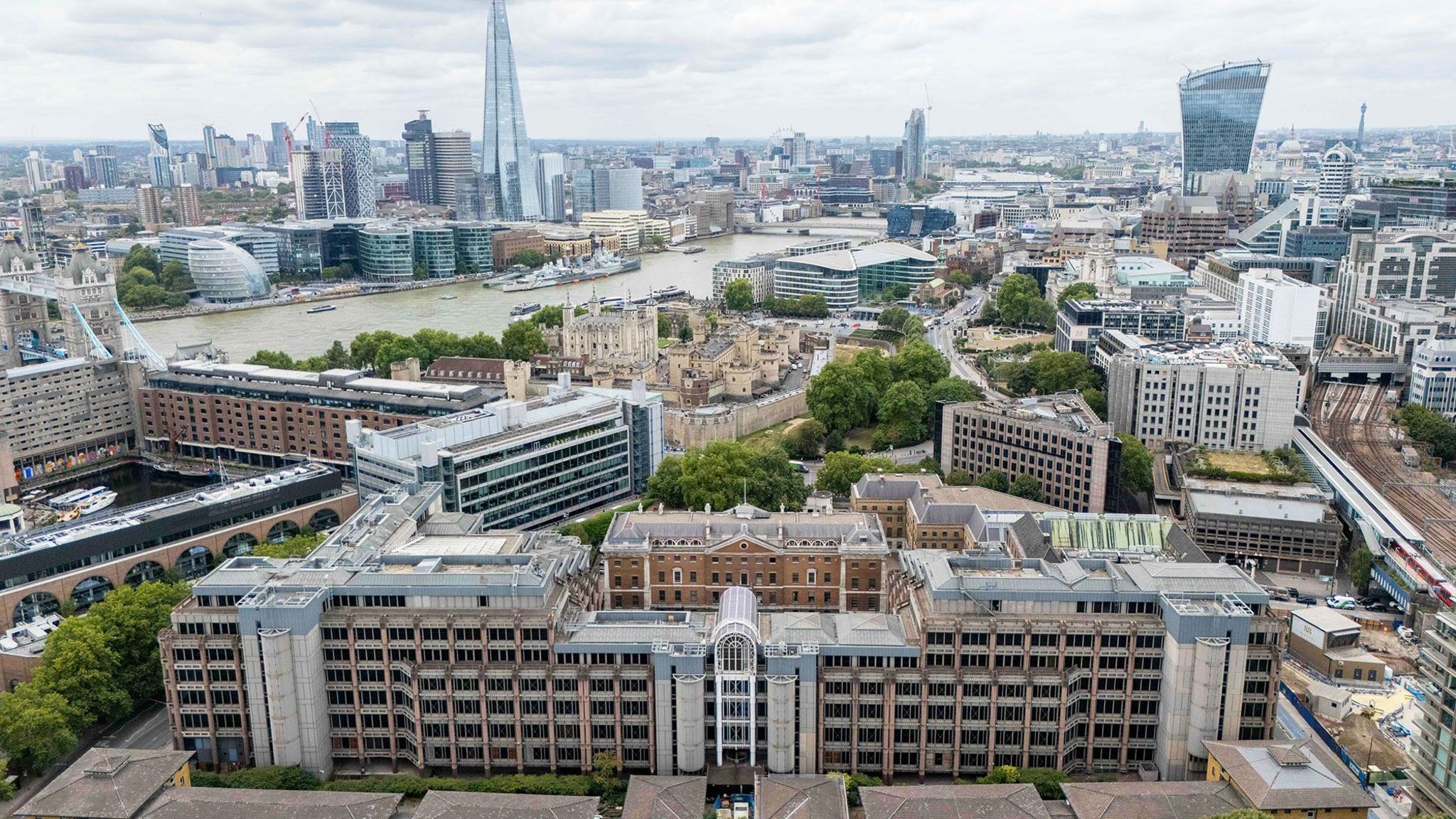 Aerial view of the old Royal Mint Court in London on a cloudy day with the River Thames, Tower of London and the Shard in the background