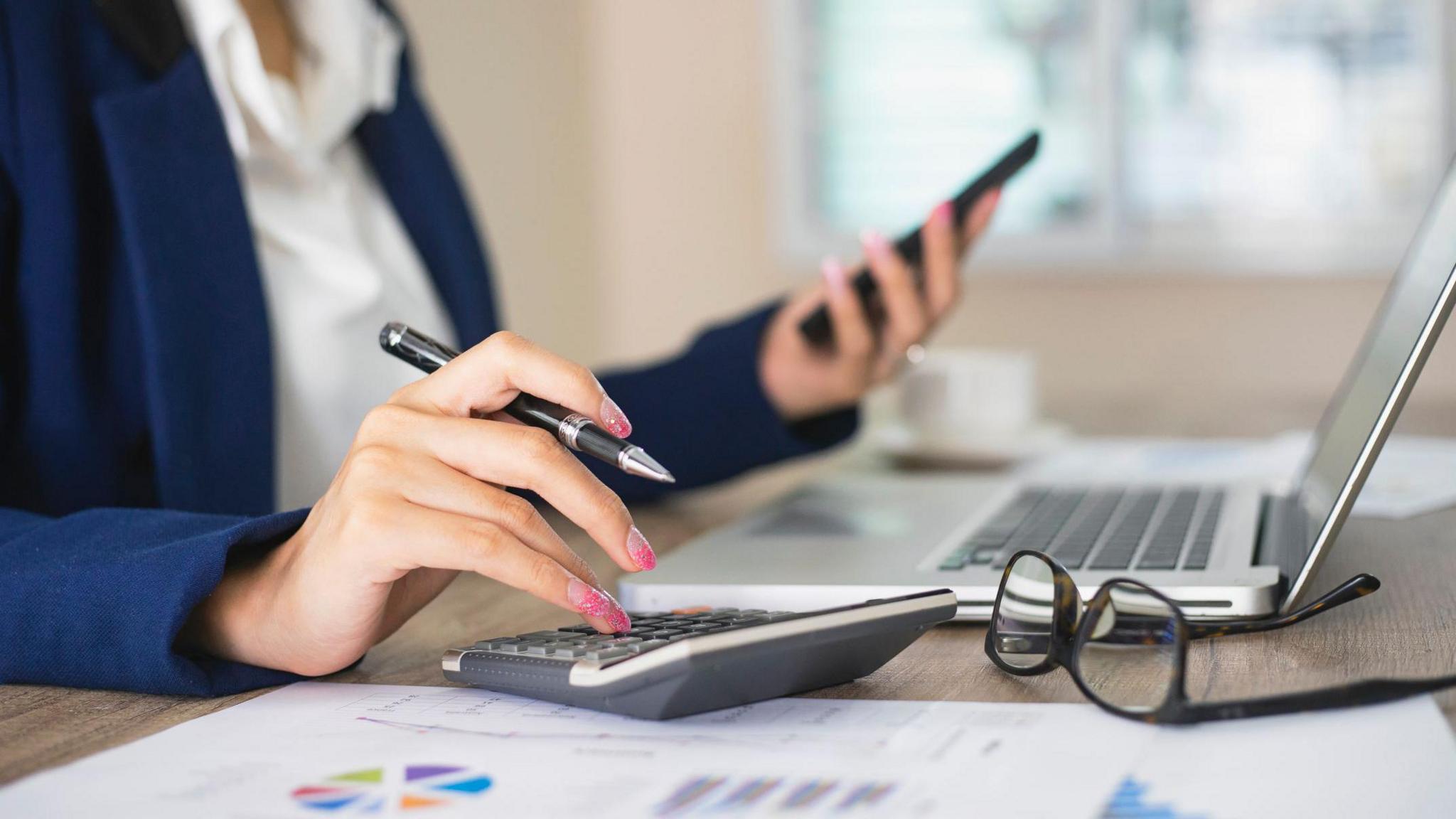 Woman using calculator and laptop