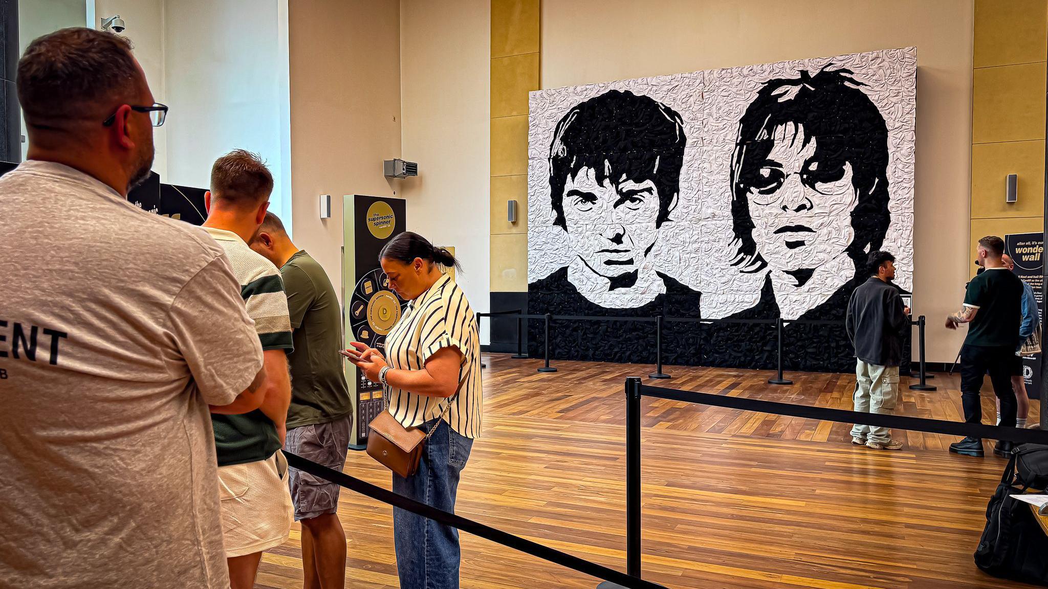 A group of people queued up in front of the mural