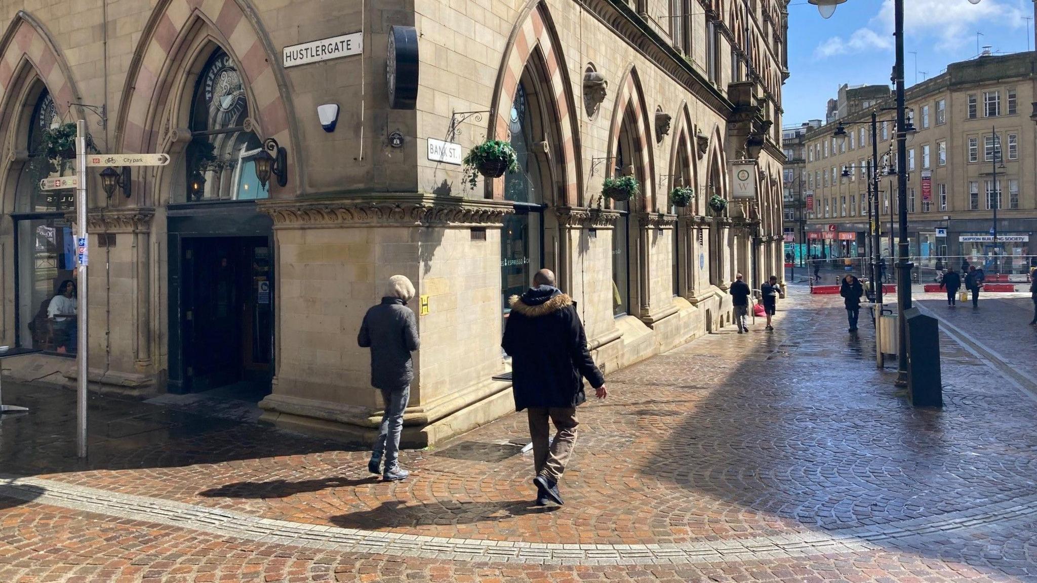 Two men walk past the junction of Hustlergate with bank Street in Bradford city centre