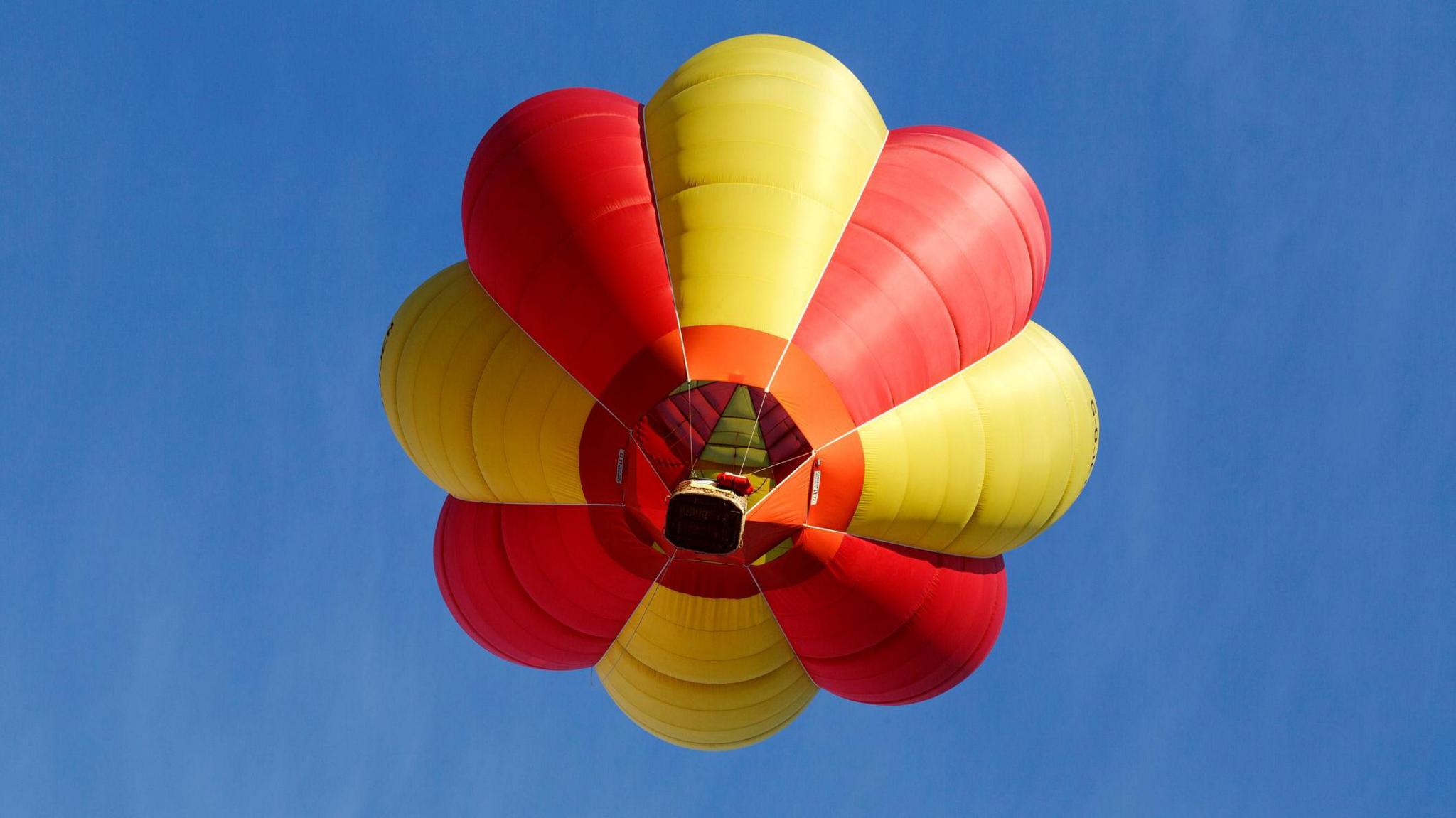 A red and yellow balloon in the sky, pictured from below.