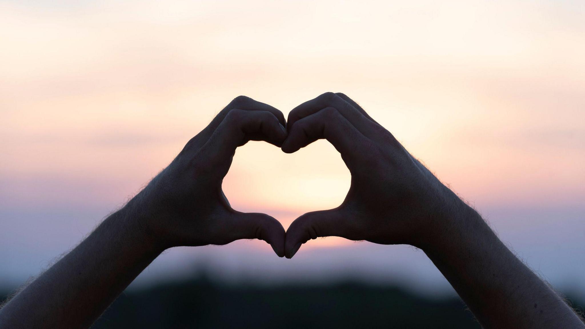 person making love heart shape with their hands