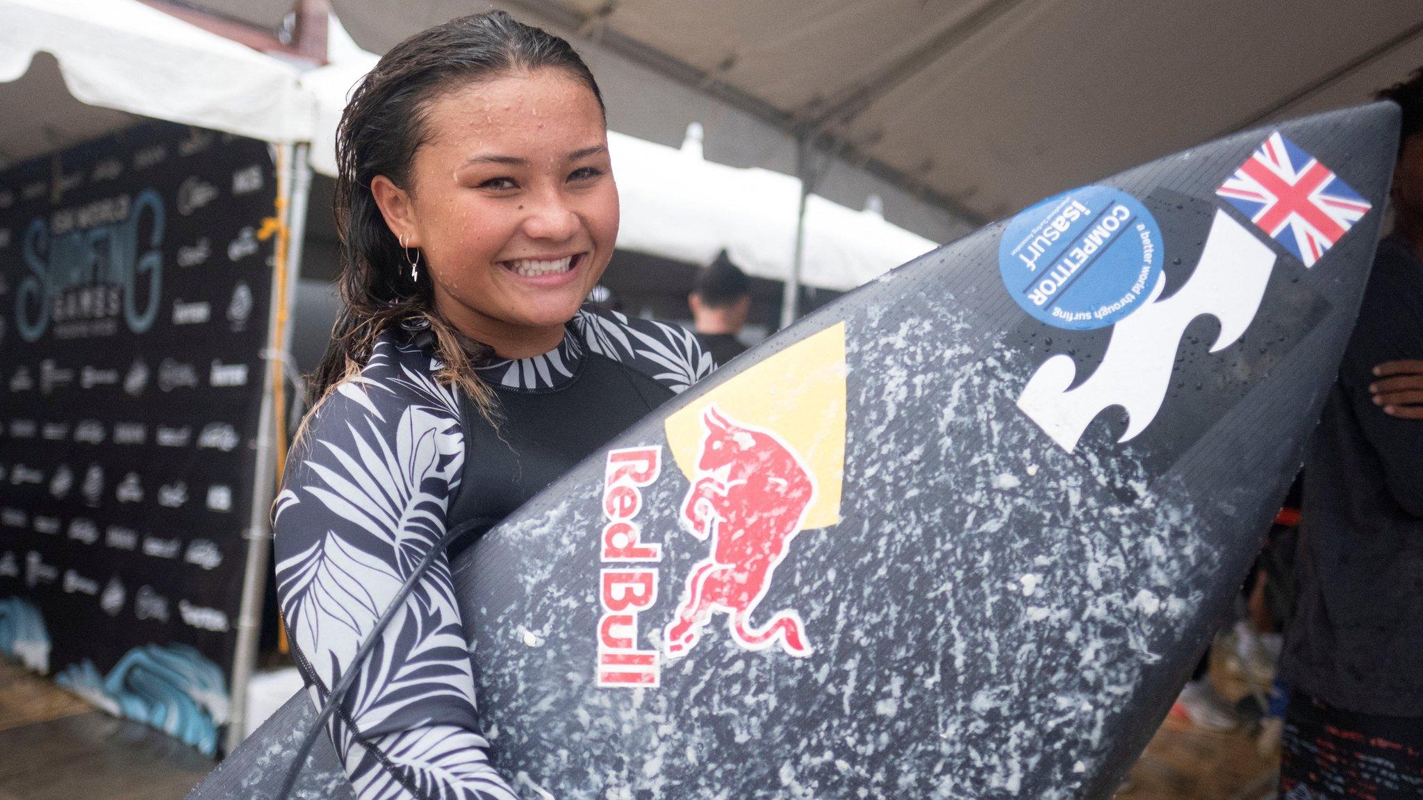 Sky Brown holding up her surfboard