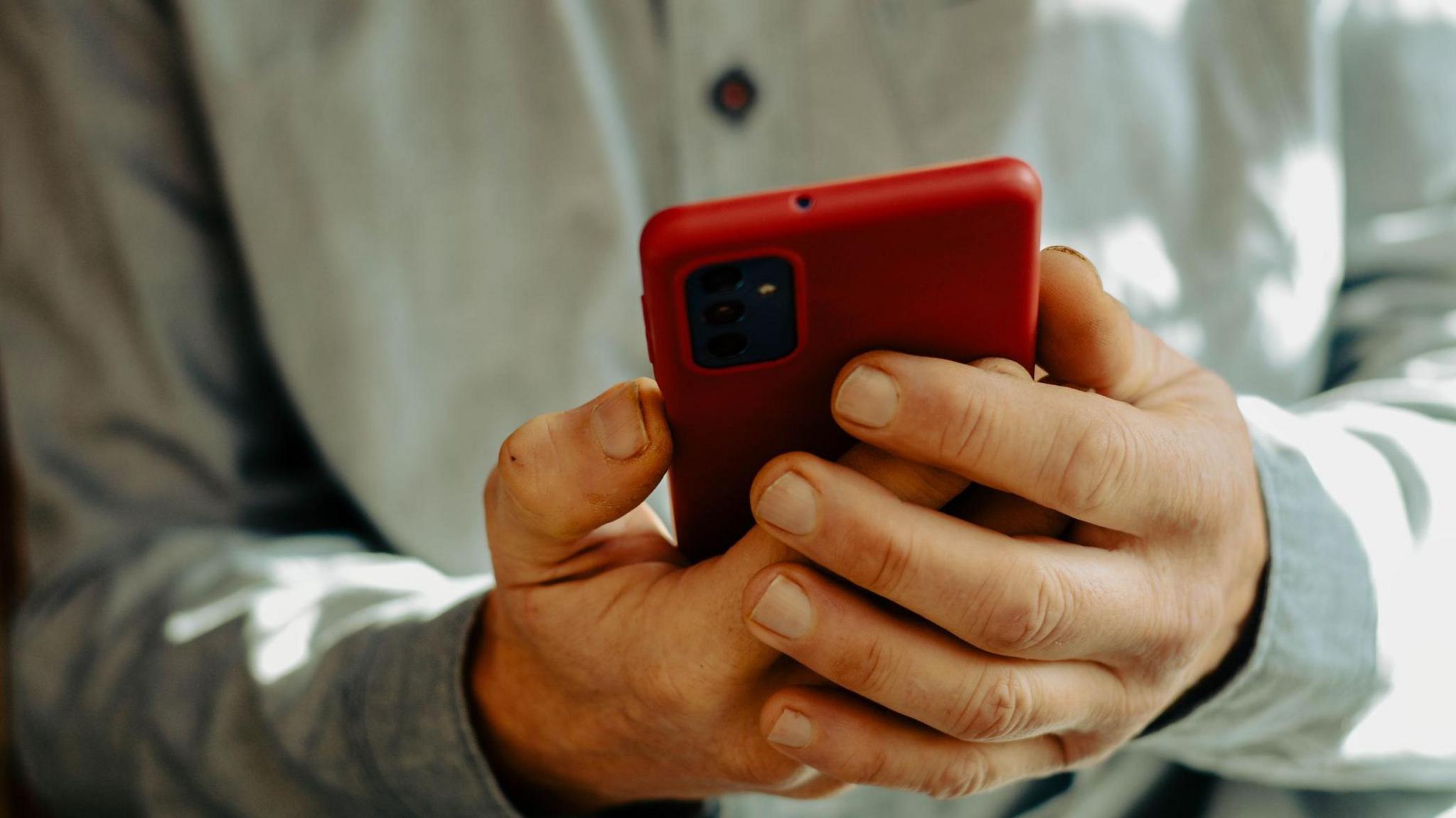 a man holding a red mobile phone 