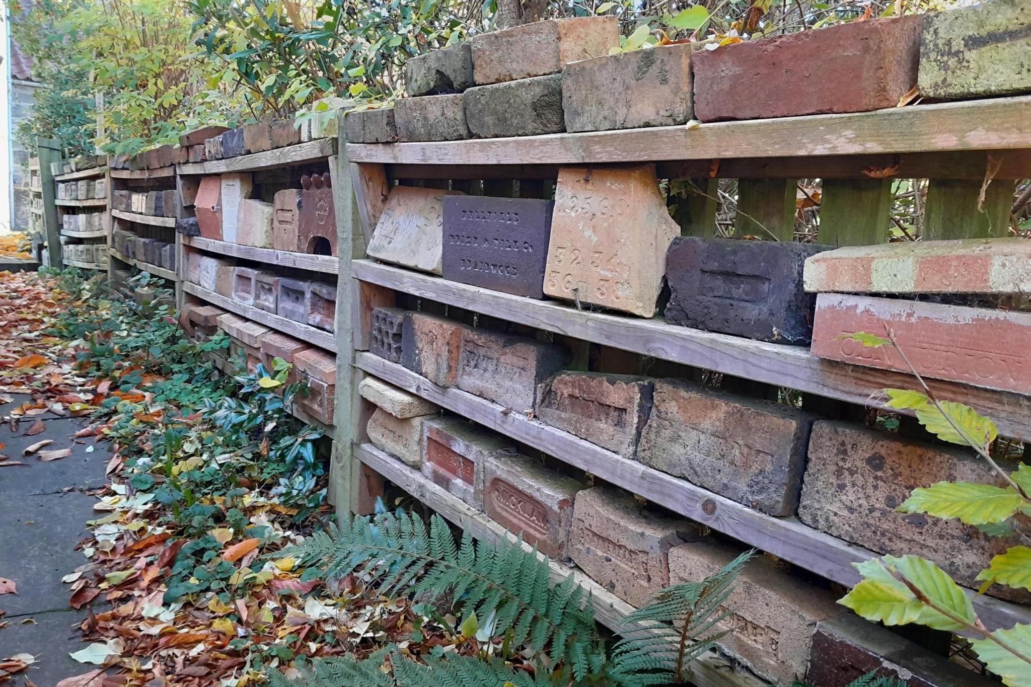 Shelves of bricks in various shades of red and brown, in garden. 