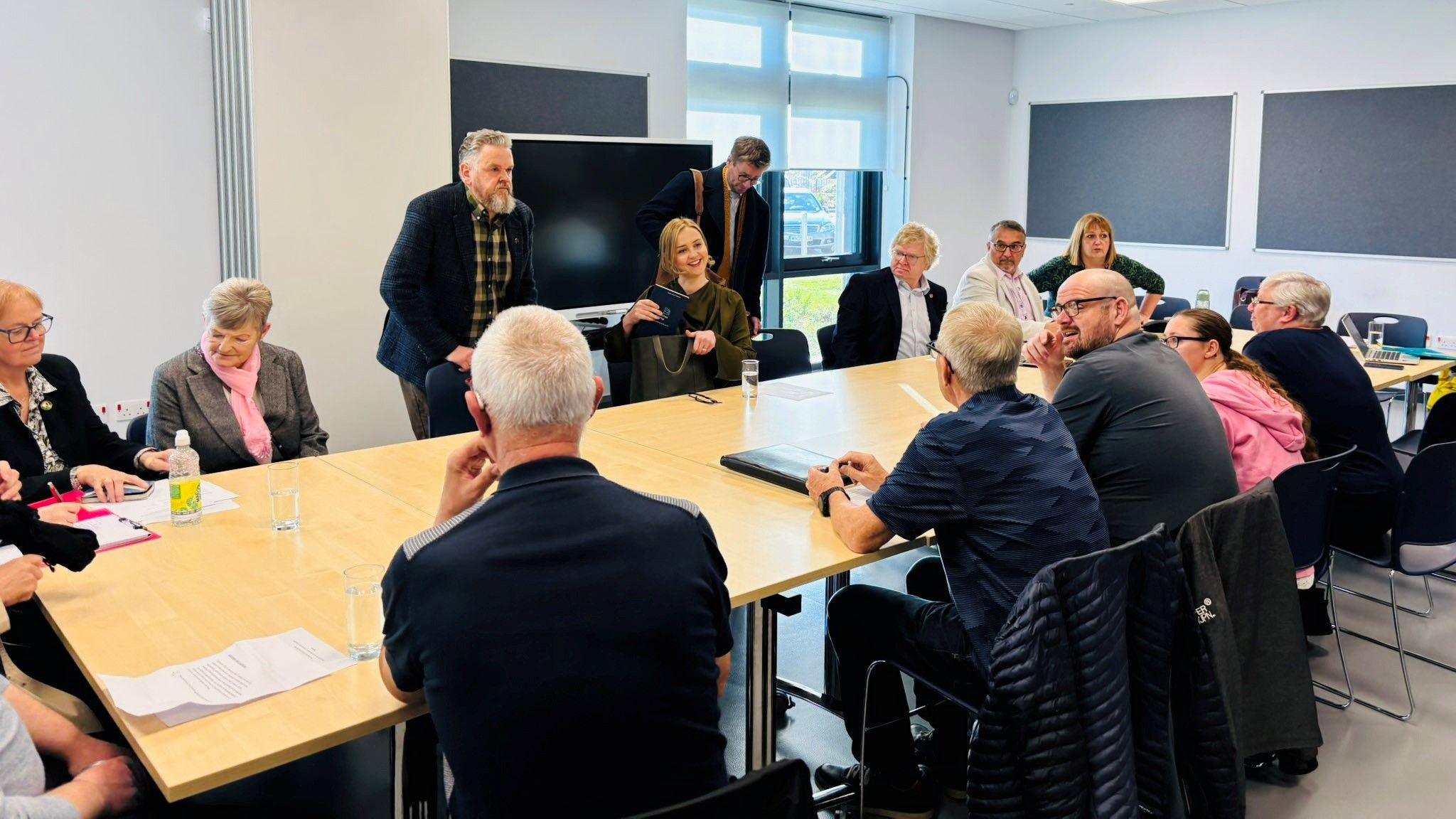 Housing secretary Màiri McAllan at a meeting table, with Aberdeen residents and councillors also seated around the table.