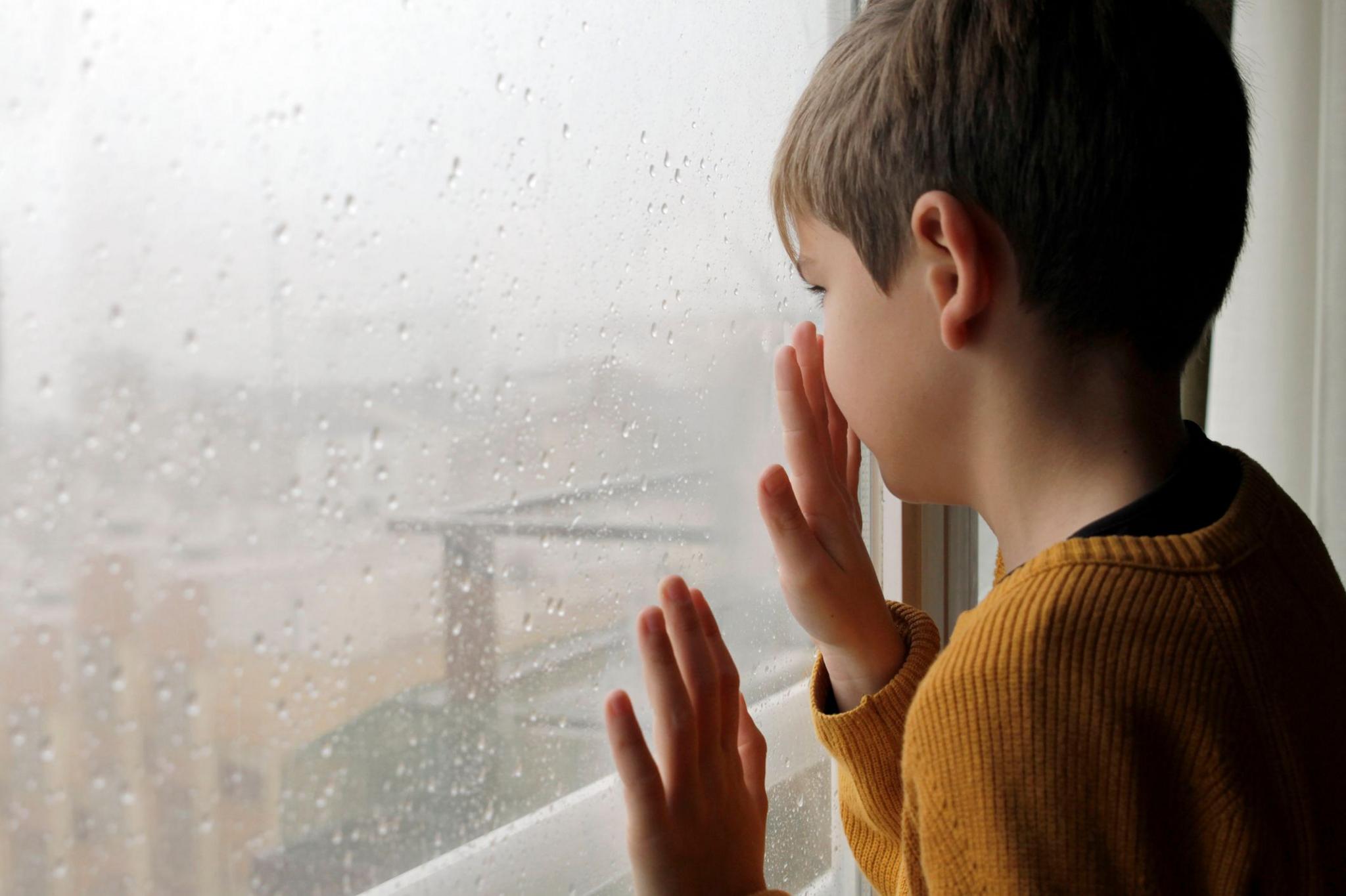 A boy looks outside during a storm
