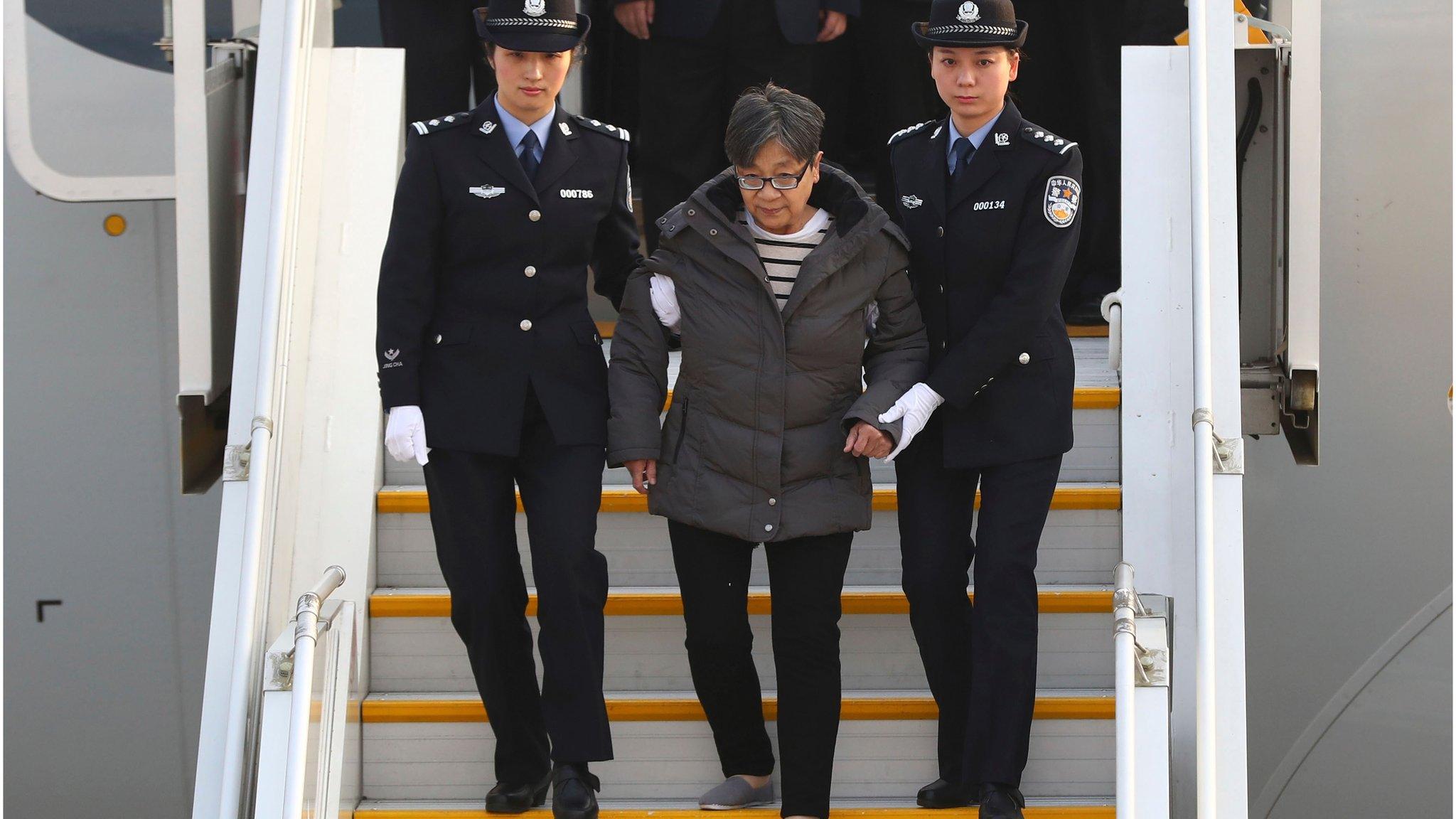 Yang Xiuzhu is escorted down a plane upon arriving at the Beijing Capital International Airport in Beijing (Nov. 16, 2016)