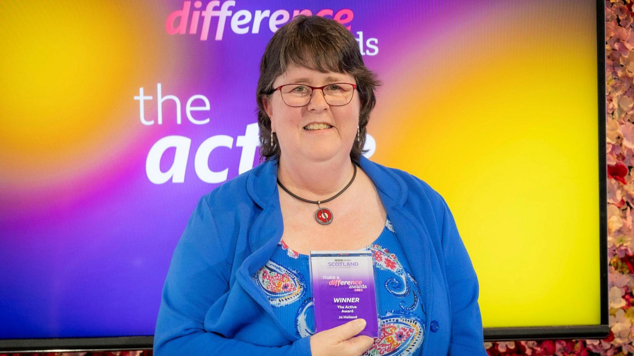 Jo Holland is standing holding her award.